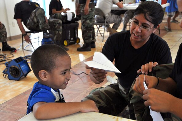 Tech. Sgt. Lisa Bartolome shows a young American Samoan boy how to make a paper airplane Oct. 2, 2009, at the Congressional Christian Church in the Fafatiua village of American Samoa. Hawaii Air National Guard members provided basic medical care to residents after a tsunami struck the island Sept. 29, 2009. The church, with the help of the government, is serving three meals a day to those that are in need. Sergeant Bartolome is assigned to the Hawaii Air National Guard's 154th Medical Group. (U.S. Air Force photo/Tech. Sgt. Cohen Young) 