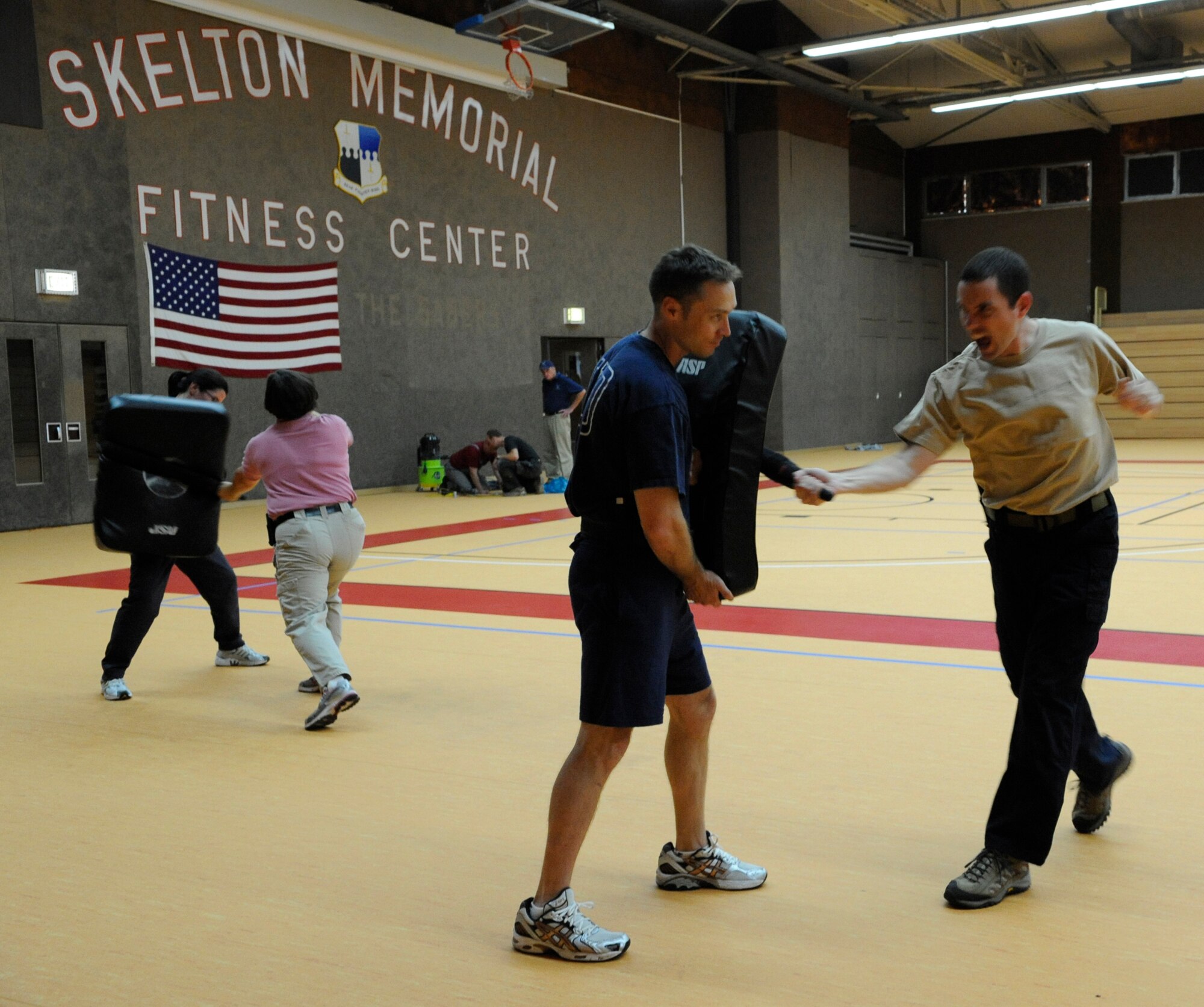 SPANGDAHLEM AIR BASE, Germany – Members of the Spangdahlem Office of Special Investigations conduct their annual baton refresher training on the Skelton Memorial Fitness Center’s new gym floor as contractors put the finishing touches on the floor Sept. 29. The fitness center replaced its gym floor with a durable and easy-to-maintain synthetic floor. The project took 60 days to complete, and it is now ready for use for wing events and physical training.  (U.S. Air Force photo/Master Sgt. Bill Gomez)