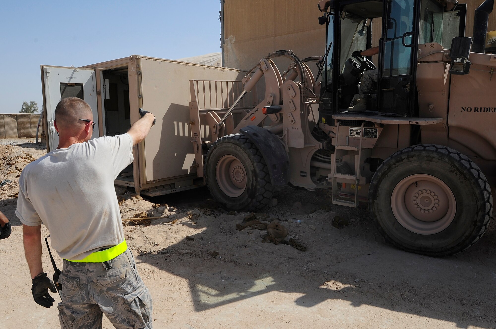 ALI BASE, Iraq – U.S. Air Force Master Sgt. Duane Patin, 407th Expeditionary Civil Engineer Squadron, ground guides a 10K forklift as it moves an expandable shelter that will be packed up and relocated, Sept. 30, 2009. The squadron has been downsizing; consolidating material and equipment to send to U.S. war fighters in Afghanistan. Sergeant Patin is deployed here from Elmendorf Air Force Base, AK. (U.S. Air Force photo/ Senior Airman Tony R. Ritter) 