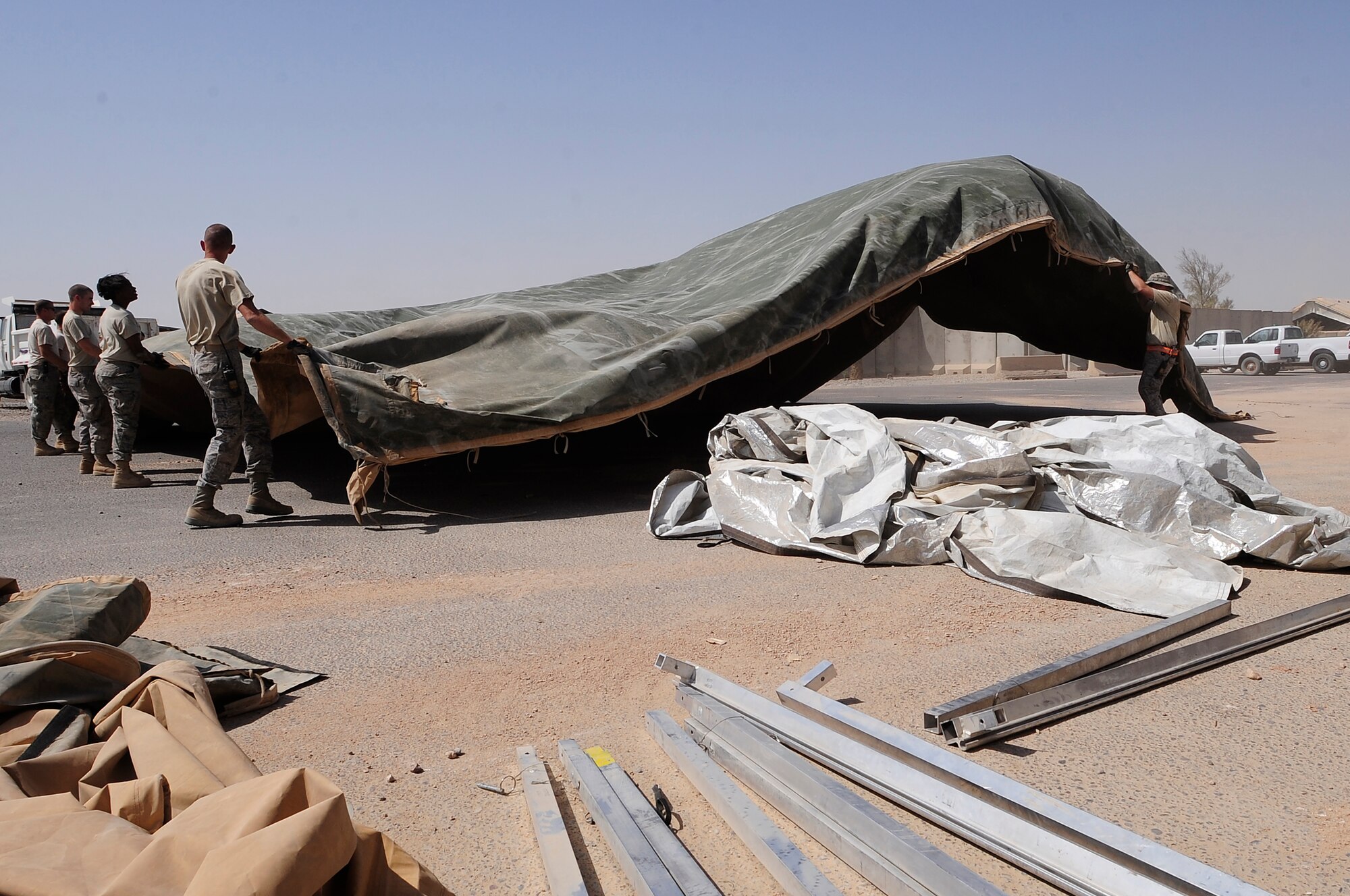 ALI BASE, Iraq – U.S. Air Force members of the 407th Expeditionary Civil Engineer Squadron take down a tent structure that had previously been used within their compound here, Sept. 30, 2009. The squadron has been downsizing; consolidating material and equipment to send to U.S. war fighters in Afghanistan. (U.S. Air Force photo/ Senior Airman Tony R. Ritter)