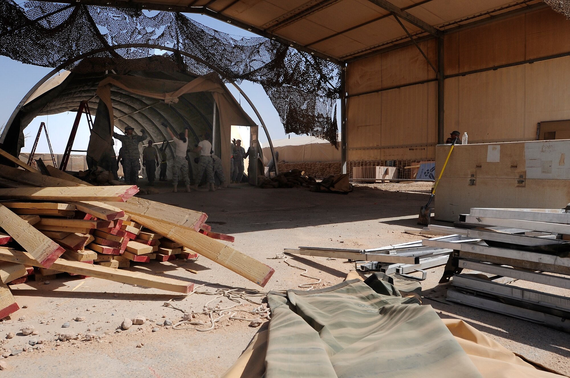 ALI BASE, Iraq – U.S. Air Force members of the 407th Expeditionary Civil Engineer Squadron take down a tent structure that had previously been used within their compound here, Sept. 30, 2009. The squadron has been downsizing; consolidating material and equipment to send to U.S. war fighters in Afghanistan. (U.S. Air Force photo/ Senior Airman Tony R. Ritter)