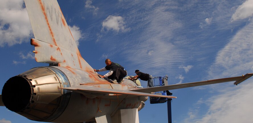 MISAWA AIR BASE, Japan— Chris Gouveia and Jim Straube, contractors, strip the old paint off an F-16 Fighting Falcon static display Oct.5 in Friendship Park. The company was contracted by the 35th Contracting Squadron to paint two F-16s, one at the Misawa Air Park and the other here at Friendship Park, in effort to control corrosion. (U.S. Air Force Photo by Staff Sgt. Phillip Butterfield)