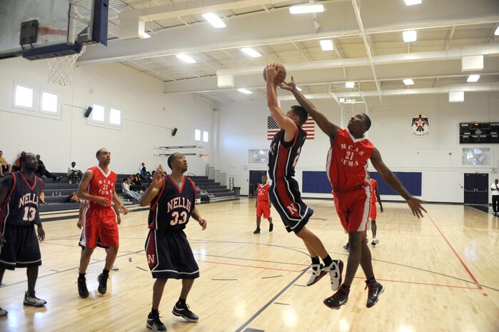 NELLIS AIR FORCE BASE, Nev.--  Lorenze Capel from Marine Corps Air Station, Yuma, Ariz., reaches over the back of J. Hall, a member of the Nellis Men's Basketball Team, during a joint service varsity basketball tournament held at the Nellis fitness center, Oct. 3.  (U.S. Air Force photo by Tech. Sgt. Michael R. Holzworth)