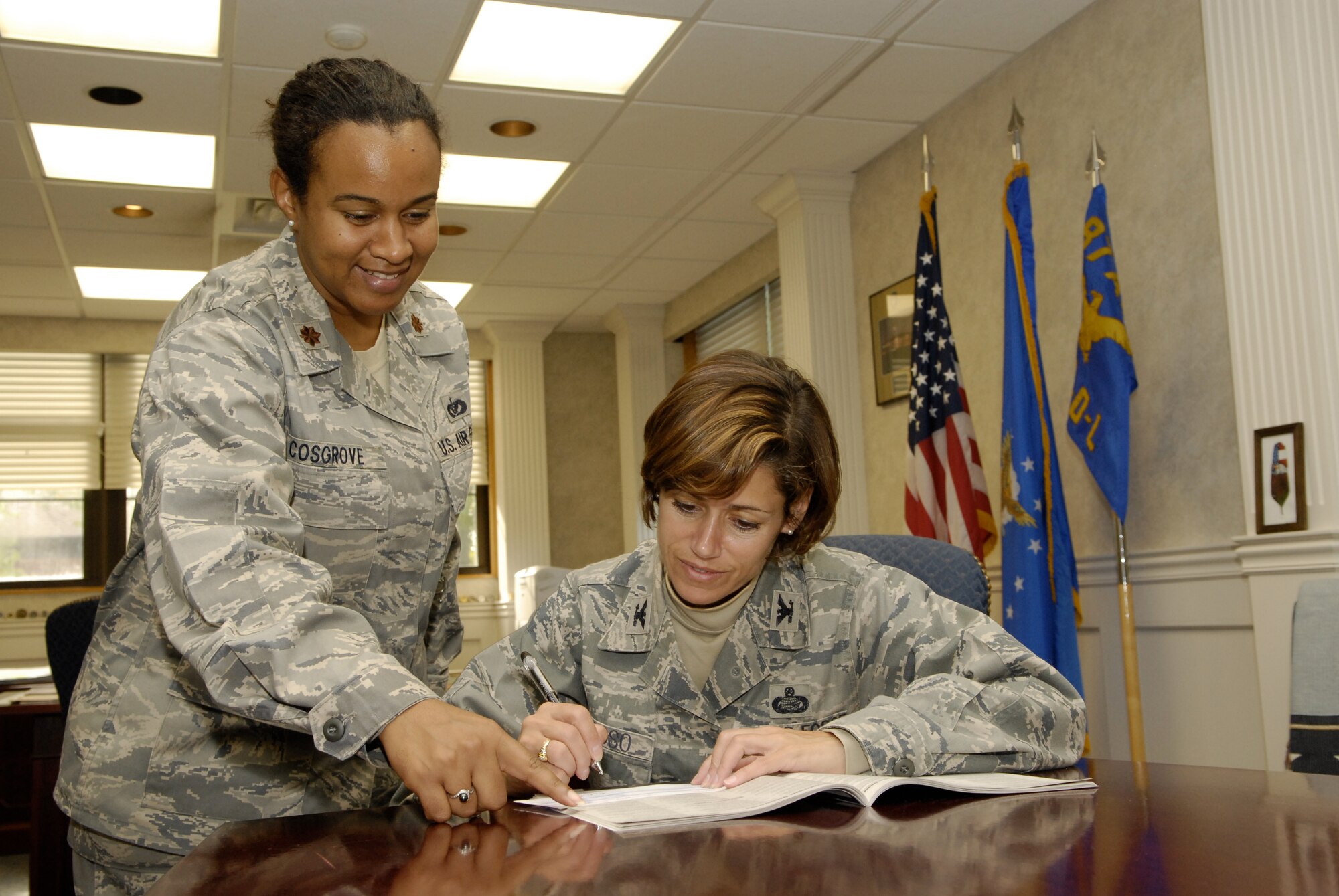 Maj. Karen Cosgrove, Joint Base McGuire-Dix-Lakehurst Combined Federal Campaign point of contact, shows  commander Col. Gina Grosso  where to sign off on the first pledge card of the year. The Combined Federal Campaign will officially launch on Oct. 15. (U.S. Air Force photo/Carlos Cintron)