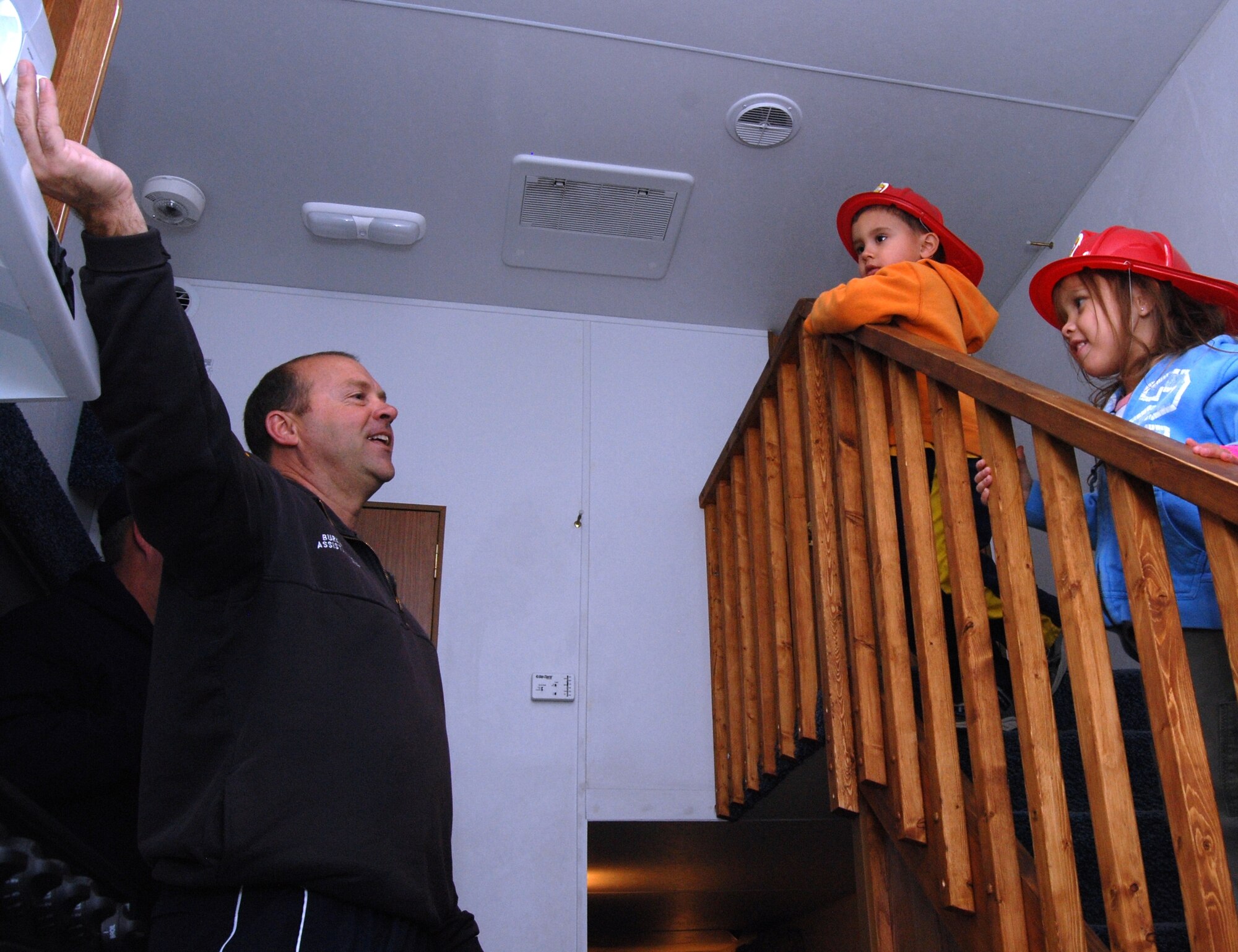 PETERSON AIR FORCE BASE, Colo. – Burke Ferrin, 21st Civil Engineer Squadron assistant chief for fire prevention, escorts four-year-old twins Leo and Chloe Morales, son and daughter of Tech. Sgt. Leo Morales, 721st Communications Squadron, through the Surrey Fire Safety House on display Oct. 3 at the base exchange to promote National Fire Prevention Week. The safety house is a compact replica of a home used by fire prevention experts to instruct children on the finer points of home fire prevention. The day’s events and displays also featured an appearance by Sparky the Fire Dog, the National Fire Protection Association’s Mascot; a fire truck display; fire extinguisher training; an education table; and a bouncy fire truck for toddlers. National Fire Prevention Week is being held by military and civilian fire departments across the United States from Oct. 4 to 10. (Air Force photo by Tech. Sgt. Ray Bowden)