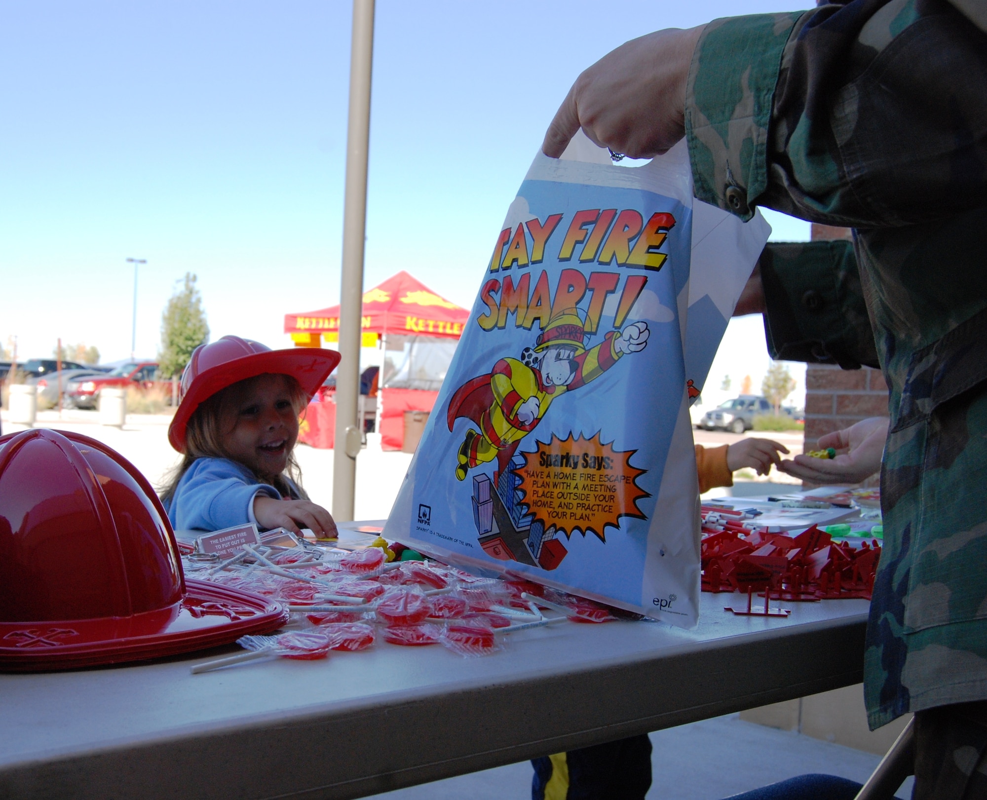PETERSON AIR FORCE BASE, Colo. – Four-year-old Chloe Morales, daughter of Tech. Sgt. Leo Morales, 721st Communications Squadron, peruses the free items that 21st Civil Engineer Squadron Airmen were giving to children Oct. 3 at the base exchange to promote National Fire Prevention Week. The day’s events also featured an appearance by Sparky the Fire Dog, the National Fire Protection Association’s mascot; a fire truck display; fire extinguisher training; a fire safety house; an education table; and a bouncy fire truck for toddlers. National Fire prevention week is being held by military and civilian fire departments across the United States from Oct. 4 to 10. (Air Force photo by Tech. Sgt. Ray Bowden)