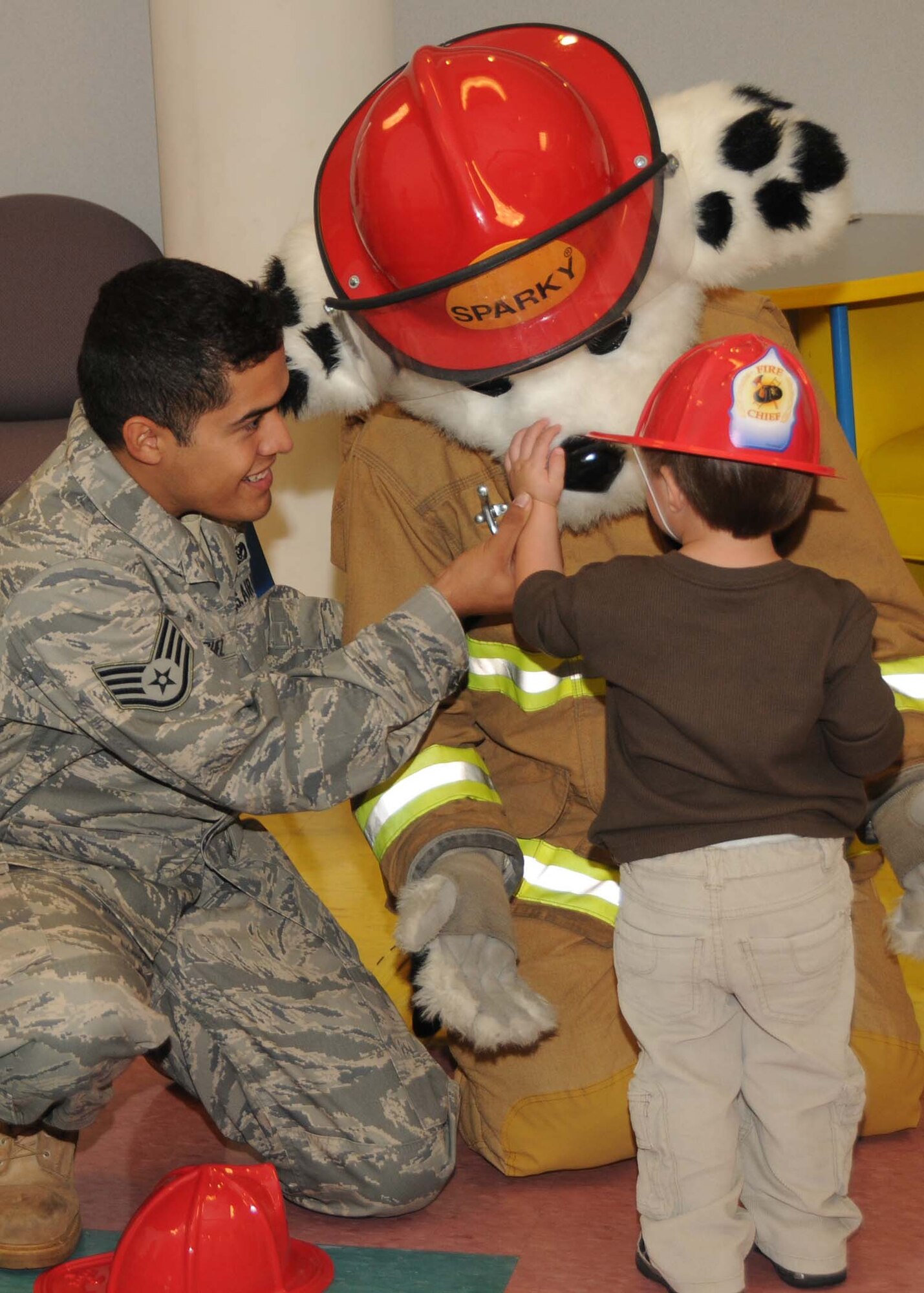 ALTUS AIR FORCE BASE, Okla. -- Staff Sgt. Gilbert Sanchez, fire fighter for the 97th Civil Engineering Squadron, and Sparky, the Fire Prevention Dog visit the Child Development Center Oct. 5. Sparky entertains the children while educating them about fire safety and passing out hats. (U.S. Air Force Photo/Senior Airman Marianne E. Lane)