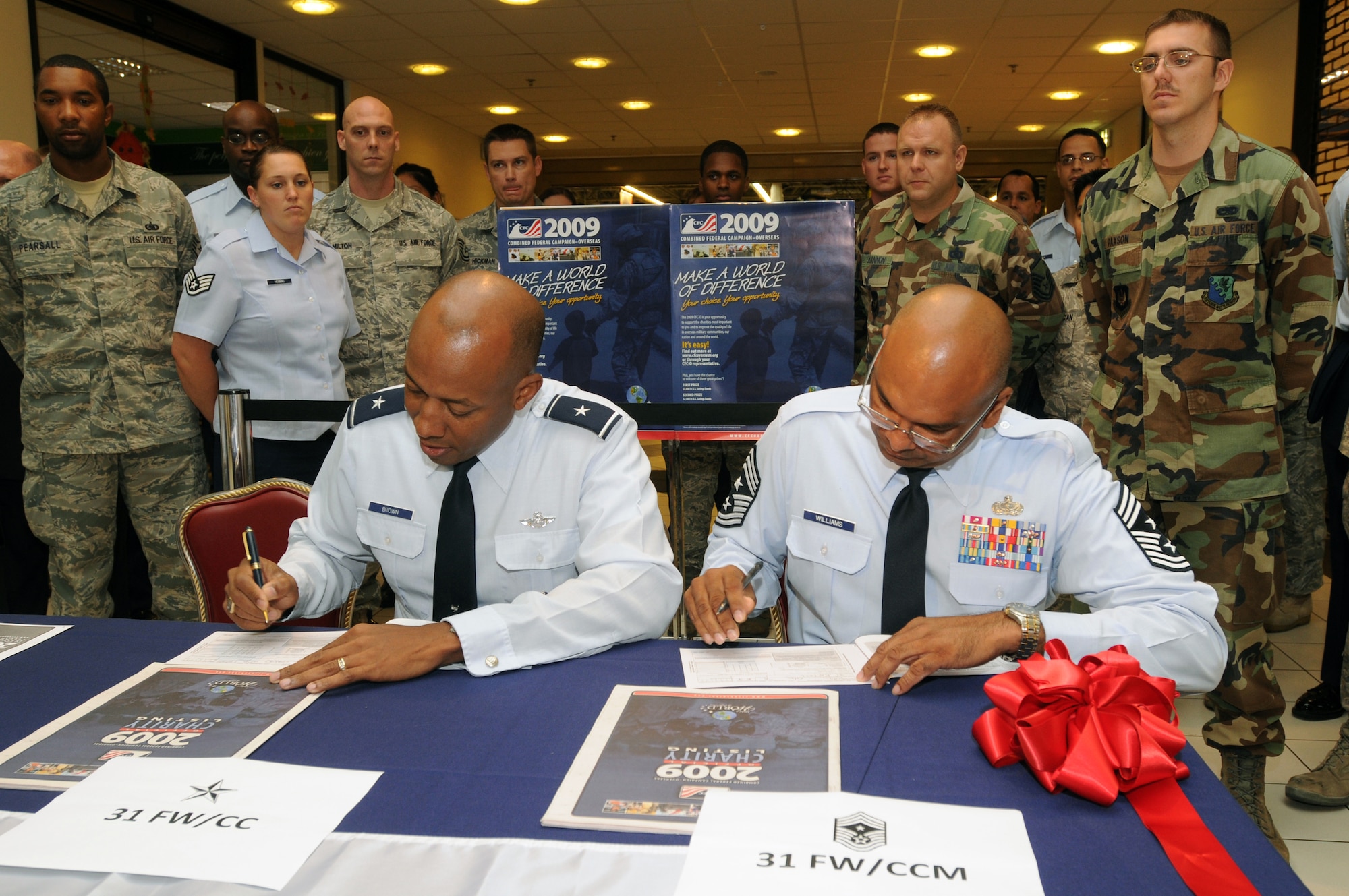 Brig. Gen.  C.Q. Brown Jr., 31st Fighter Wing commander, and Chief Master Sgt. Laten D. Williams, 31st FW command chief, sign their Combined Federal Campaign contribution forms during the base CFC kick off ceremony Oct. 5, 2009, in the base exchange at Aviano Air Base, Italy. (U.S. Air Force photo/ Staff Sgt. Patrick Dixon)