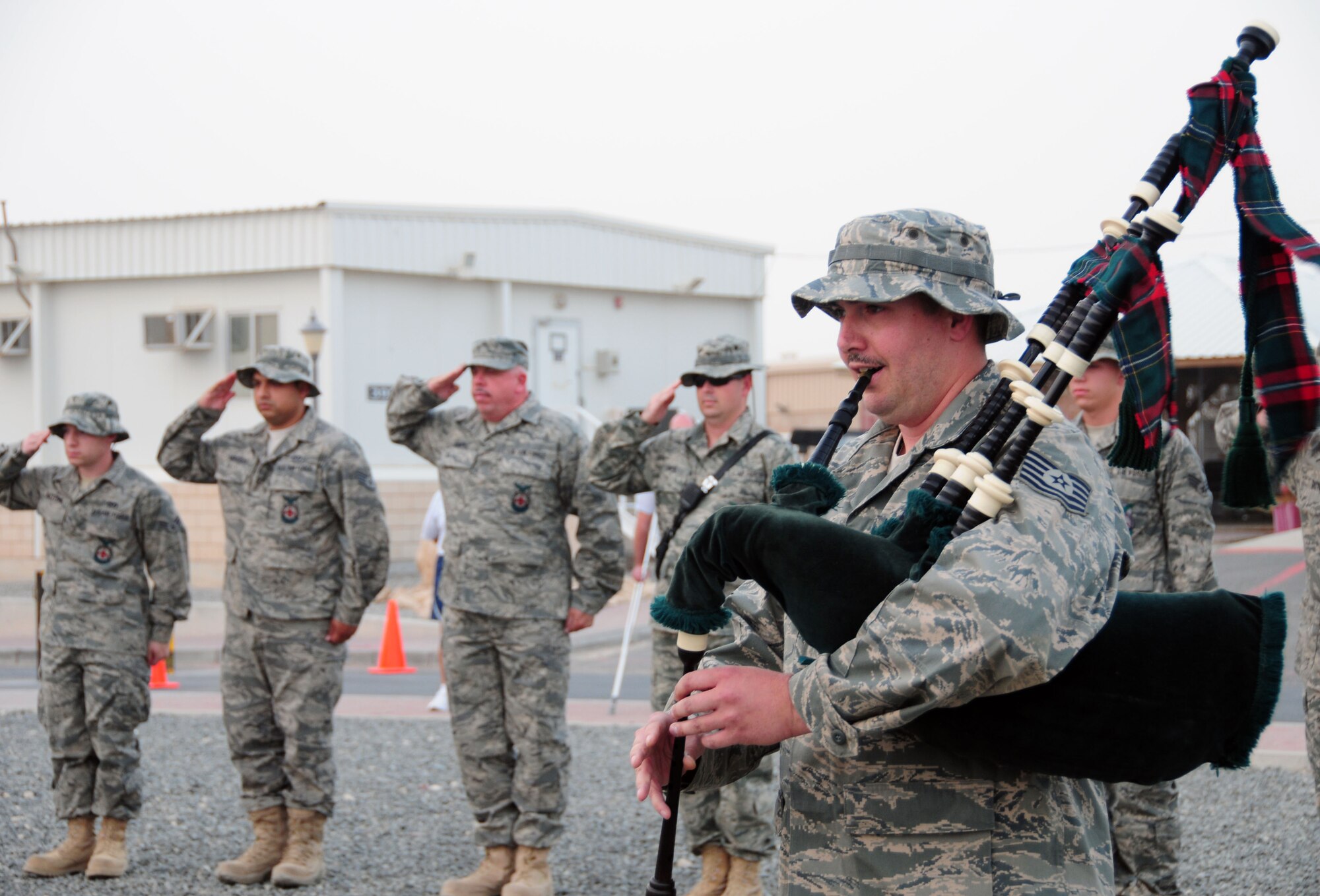SOUTHWEST ASIA --  Members of the 386th Expeditionary Civil Engineer Squadron Fire Protection Flight render a salute as Tech. Sgt. Jesse Painter, 386th ECES  firefigher, plays Amazing Grace on the bag pipes in honor of National Fallen Firefighters Day Oct. 4, 2009. Sergeant Painter is deployed from the 11th Fighter Wing, Willow Grove, Pennsylvania and is a firefighter with the Philadelphia Fire Department. (U.S. Air Force photo/Staff Sgt. Shaun Emery)