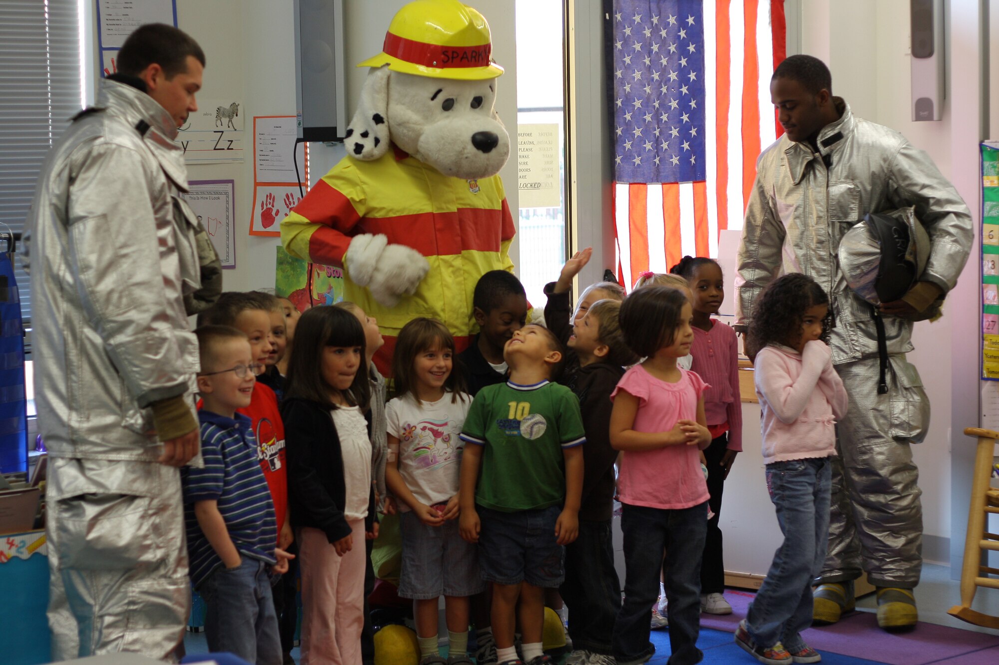 Sparky the Fire Dog joins Airmen 1st Class William Stone (left) and Joshua Gray, 31st Civil Engineer Squadron firefighters, during a visit with Aviano Elementary School kindergarteners Sept. 28, 2009 at Aviano Air Base, Italy, as part of National Fire Prevention Week. The focus of the visit was to teach the children about fire safety in the home, cooking burns and evacuation procedures. (U.S. Air Force photo)