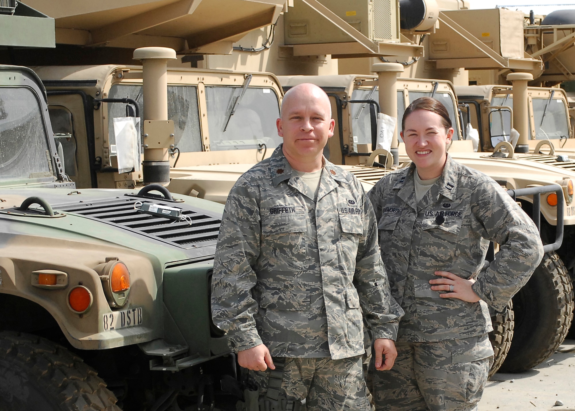 BAGRAM AIRFIELD, Afghanistan -- Major Tobin Griffeth and Capt. Katie Illingworth, Contract and Fiscal lawyers with Combined Joint Task Force 82's Office of the Staff Judge Advocate stand together in front of a large group of Humvees.  Major Griffeth and Captain Illingworth created a game that would harness the energy of fan support for the University's of Texas and Oklahoma's heated rivalry.  Donations of clothes, shoes and school supplies are sent in to the duo where the help distribute it country-wide to ground patrols to help the Afghan people.  "This war will be one person at a time, and through the children," Major Griffeth said.  (U.S. Air Force/Senior Airman Felicia Juenke)
