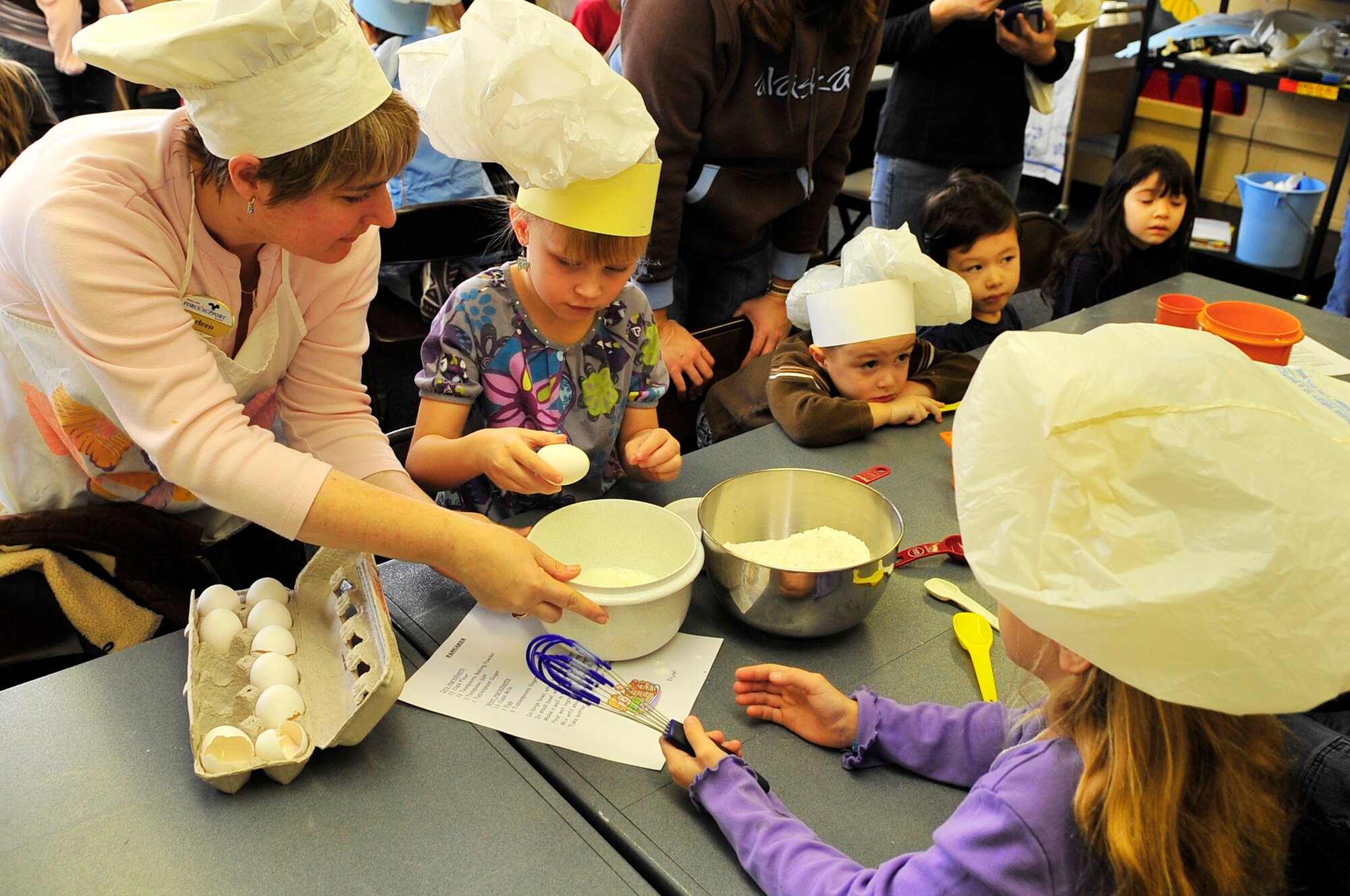 Karleen Jacobson assists children with preparing pancakes at the library during the 2nd annual "Book 'Em and Cook 'Em" program Oct. 3, 2009, Eielson Air Force Base, Alaska. The program entertained more than 40 children who were read stories and then prepared the meal that was read to them. Mrs. Jacobson is a library technician assigned to the 354th Force Support Squadron. (U.S. Air Force photo/Staff Sgt. Christopher Boitz)