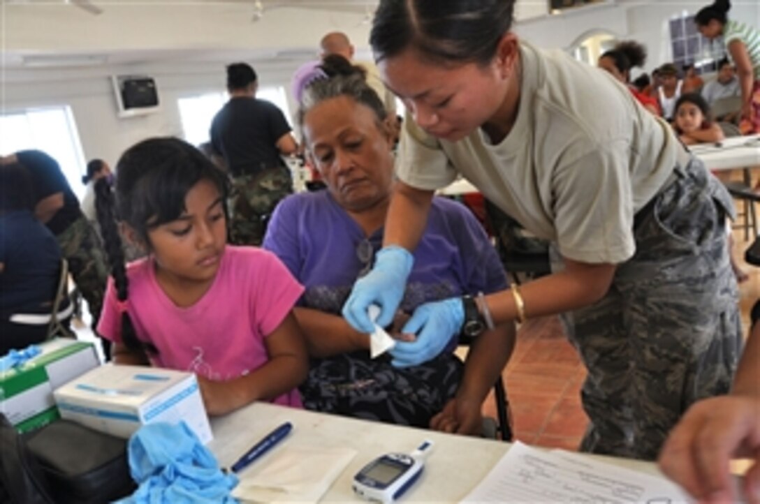 U.S. Air Force Airman 1st Class Jenalyn Balcobero, from the Hawaii Air National Guard’s 154th Medical Group, wipes the finger of an American Samoan woman after checking her blood sugar levels at the Congressional Christian Church of American Samoa in Fagatitua, American Samoa on Oct. 2, 2009.  A multi-agency contingent from Hawaii including active duty and National Guard soldiers and airmen are deployed to provide humanitarian assistance after tsunamis triggered by an undersea earthquake on Sept. 29, 2009, left more than 140 people dead in the South Pacific region.  