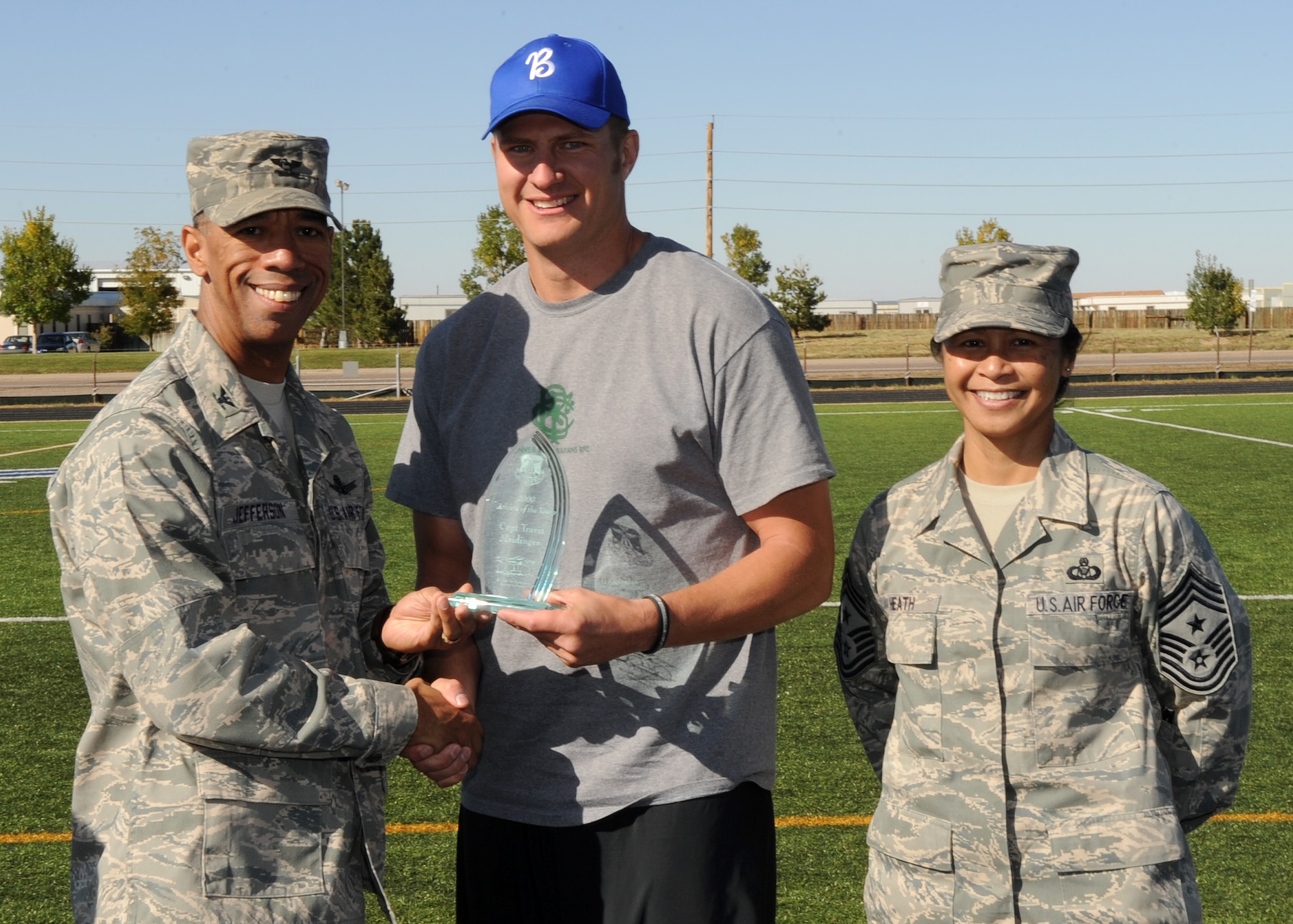 Buckley Air Force Base, Colo. – Col. Vincent Jefferson, 460th Mission Support Group commander, and Chief Master Sergeant Arleen Heath, 460th Space Wing command chief, present Travis Meidinger Buckley’s 2009 Athlete of the Year trophy during the awards ceremony for Buckley’s Sports and Field Day. Meidinger will now compete for Air Force Space Command Athlete of the Year. (U. S. Air Force photo by Senior Airman John Easterling)