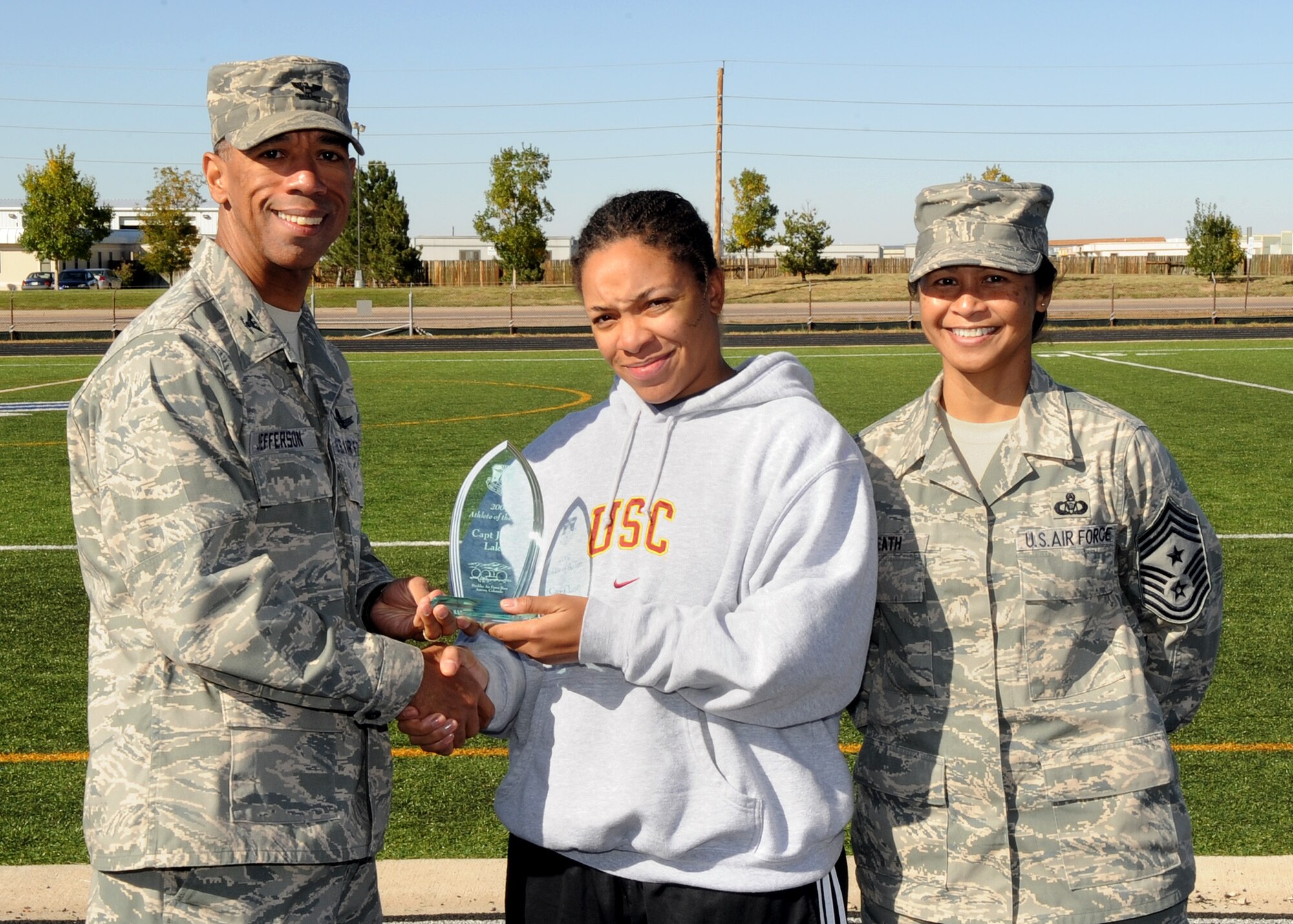 Buckley Air Force Base, Colo. – Col. Vincent Jefferson, 460th Mission Support Group commander, and Chief Master Sergeant Arleen Heath, 460th Space Wing command chief, present Janay Lake Buckley’s 2009 Athlete of the Year trophy during the awards ceremony for Buckley’s Sports and Field Day. Lake will now compete for Air Force Space Command Athlete of the Year. (U. S. Air Force photo by Senior Airman John Easterling)