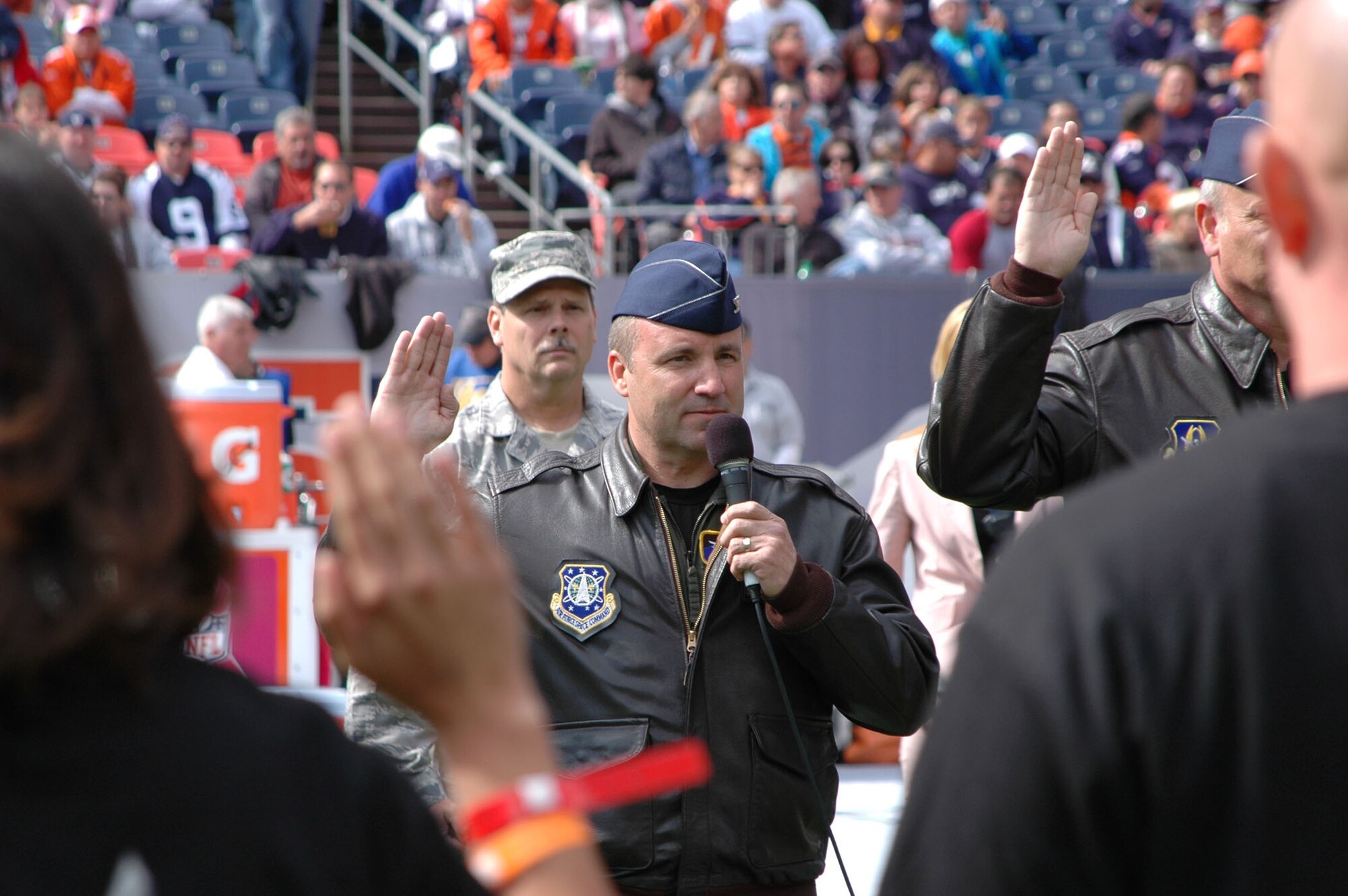 Cols. Mark Hustedt (center) and Bob Chapman present the oath of enlistment to Air Force Reserve recruits Oct. 4 during the pre-game activities of the Denver Broncos-Dallas Cowboys NFL game at Invesco Field in Denver. The Air Force Reserve enlistment was hosted by both the 310th Space Wing and 302nd Airlift Wing, both based in Colorado Springs, Colo. The recruits took the oath of enlistment in front of a crowd of more than 76,400 fans. Colonel Chapman is the 302nd AW's vice commander, while Colonel Hustedt is the space wing's vice commander. (U.S. Air Force photo/Tech. Sgt. Daniel Butterfield)