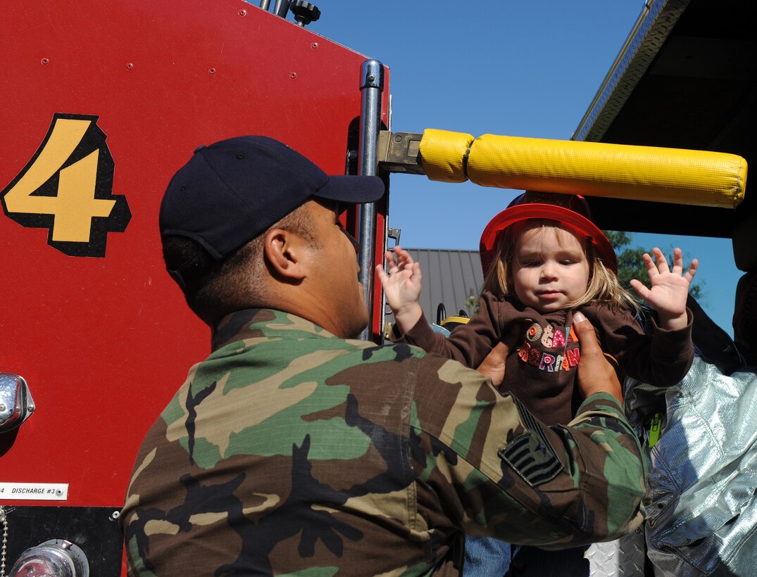 LANGLEY AIR FORCE BASE, Va. -- Tech. Sgt. A.J. Eversley, 1st Civil Engineer Squadron firefighter, lifts Abby Guest, daughter of 1st Lt. Jeremy Guest, 1st Civil Engineer Squadron readiness chief, off the fire truck here Oct. 7.   Base firefighters are teaching children about fire safety during Fire Prevention Week, Oct. 4-10.   (U.S. Air Force photo/Senior Airman Zachary Wolf)