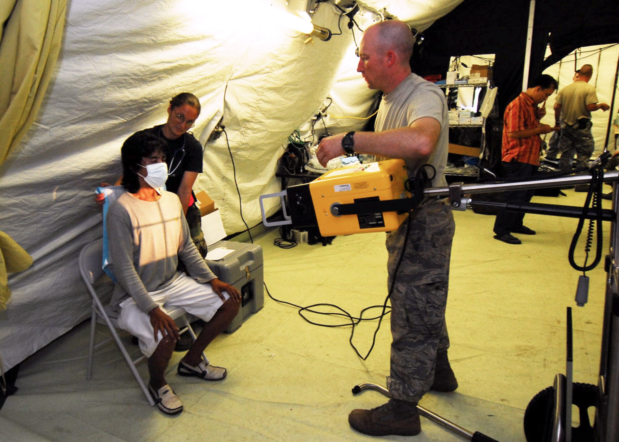 PADANG, Indonesia -- Air Force Humanitarian Assistance Rapid Response Team members Tech. Sgt. China Mills (left) and Staff Sgt. Clifford Gentry x-ray a man's chest Oct. 7. The HARRT has set up a mobile field hospital to provide medical care to those injured by the recent earthquakes here. Sergeant Mills is an individual duty medical technician from the 374th Surgical Operations Squadron at Yokota Air Base, Japan. Sergeant Gentry is a medical technician from the 36th Medical Operations Squadron at Andersen Air Force Base, Guam. (U.S. Air Force photo/Staff Sgt. Veronica Pierce)