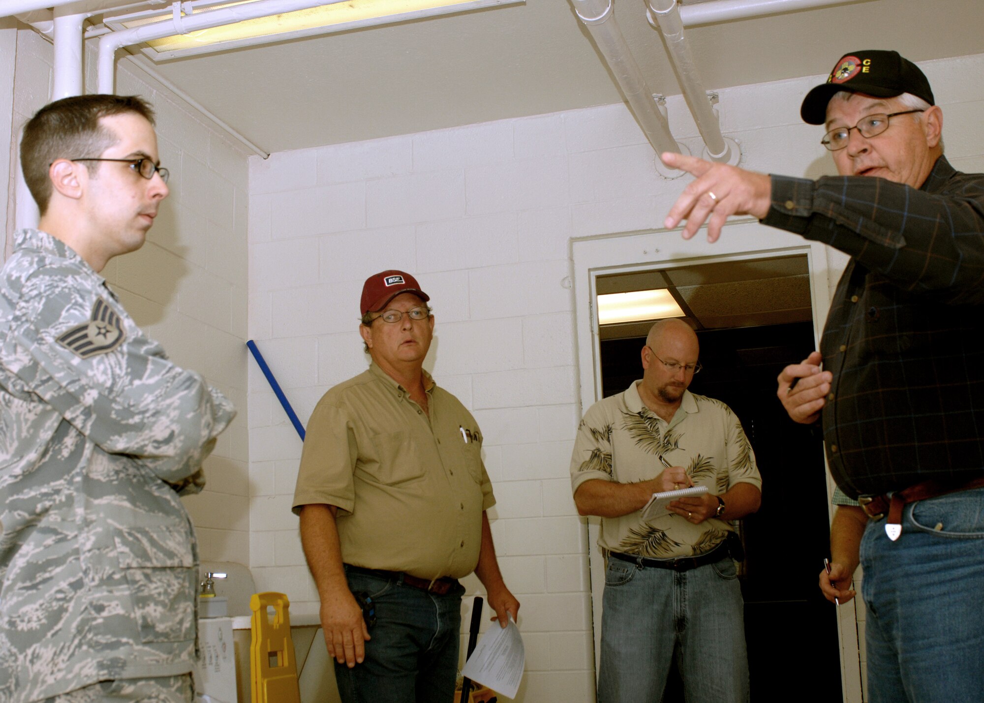 CANNON AIR FORCE BASE, N.M.-- Gerald Pelfrey, 27th Special Operations Civil Engineer Squadron, points to areas in a laundry room that will be modernized by contracting firm D.W.G. & Associates. (Left to right) Staff Sgt. Andre Casiano, 27th Special Operations Contracting Squadron, Wilbur Jones, D.W.G. & Associates, and Robert Beaudry, 27 SOCONS listen and take notes for the project that will provide new plumbing, ventilation, lights and walls.  (U.S. Air Force photo by Airman 1st Class James Bell) 