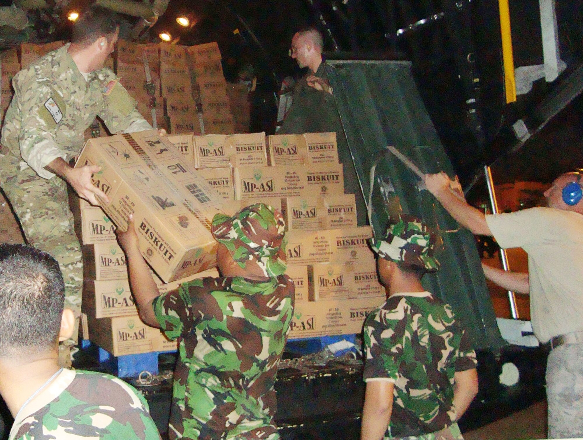 Members of the 353rd Special Operations Group and Indonesian air force members unload relief supplies from a MC-130P Combat Shadow Oct. 2, 2009, at Padang, Indonesia. Members of group immediately started moving emergency response teams, equipment and relief supplies to the Padang area to support humanitarian relief operations after a 7.6 magnitude earthquake and a slightly smaller one struck the area Sept. 29 and Oct. 1. The 353rd SOG Airmen are from Kadena Air Base, Japan. (Courtesy photo) 