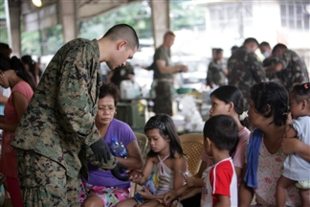 U.S. Navy Petty Officer 2nd Class Raulito Galgana, with III Marine Expeditionary Force, hands a patient medicine at an evacuation center in the Philippines on Oct. 2, 2009.  U.S. service members are providing medical and dental assistance to flood victims in the area.  Flooding caused by several typhoons has destroyed homes and has displaced thousands of residents.  