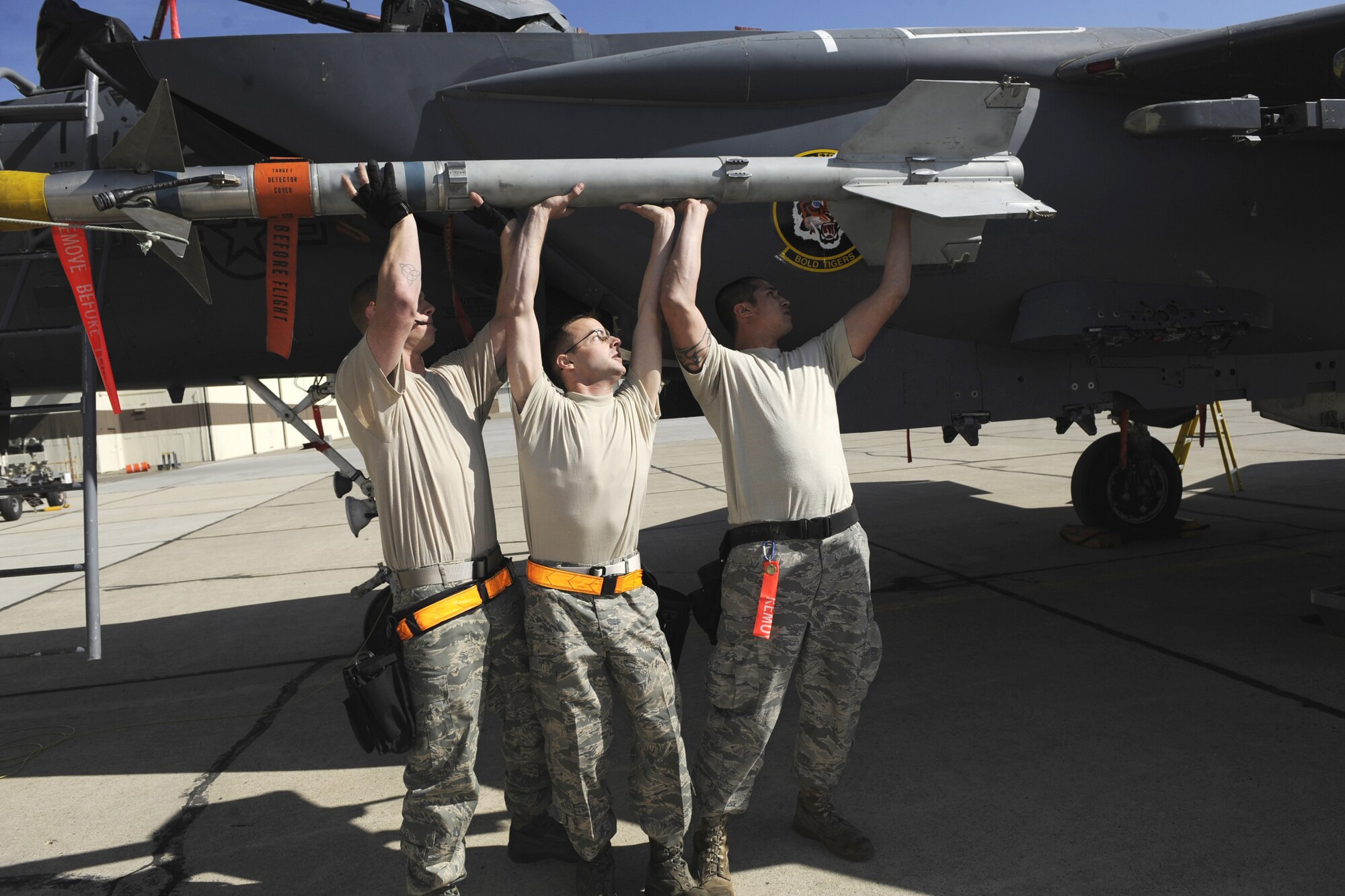 MOUNTAIN HOME AIR FORCE BASE, Idaho -- Left, Staff Sgt. David Foster, Senior Airman Robert Pennok and Senior Airman Phillip Koehn, all 391st Aircraft Maintenance  Unit weapons load crew members, load the AIM-9LM sidewinder onto the F-15E Strike Eagle during the Weapons Load Crew Competition Oct. 2. The 428th Fighter Squadron took its first victory winning the competition by only one point. (U.S. Air Force photo by Airman 1st Class Renishia Richardson)