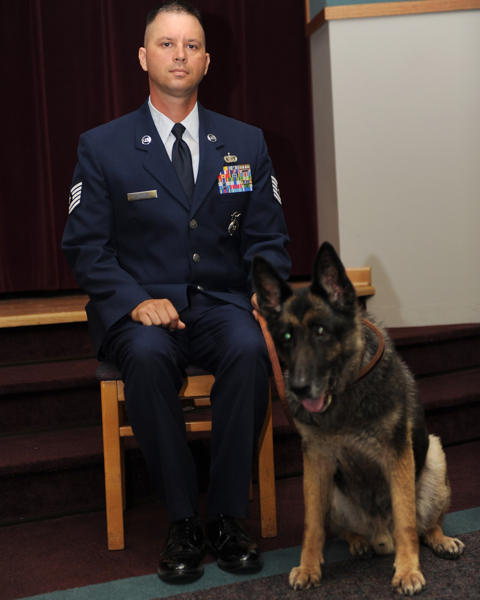 WHITEMAN AIR FORCE BASE, Mo. – Military Working Dog, Joost sits next to his escort Tech. Sgt. Brian Hudson, 509th Security Forces Squadron MWD handler, during Joost's retirement ceremony from active duty, Oct 8. MWDs Charlie, Joost, Rico, and Tina retired from active duty service Oct. 8 after more than 35 years of service to their country combined. (U.S. Air Force Photo/ Senior Airman Cory Todd)