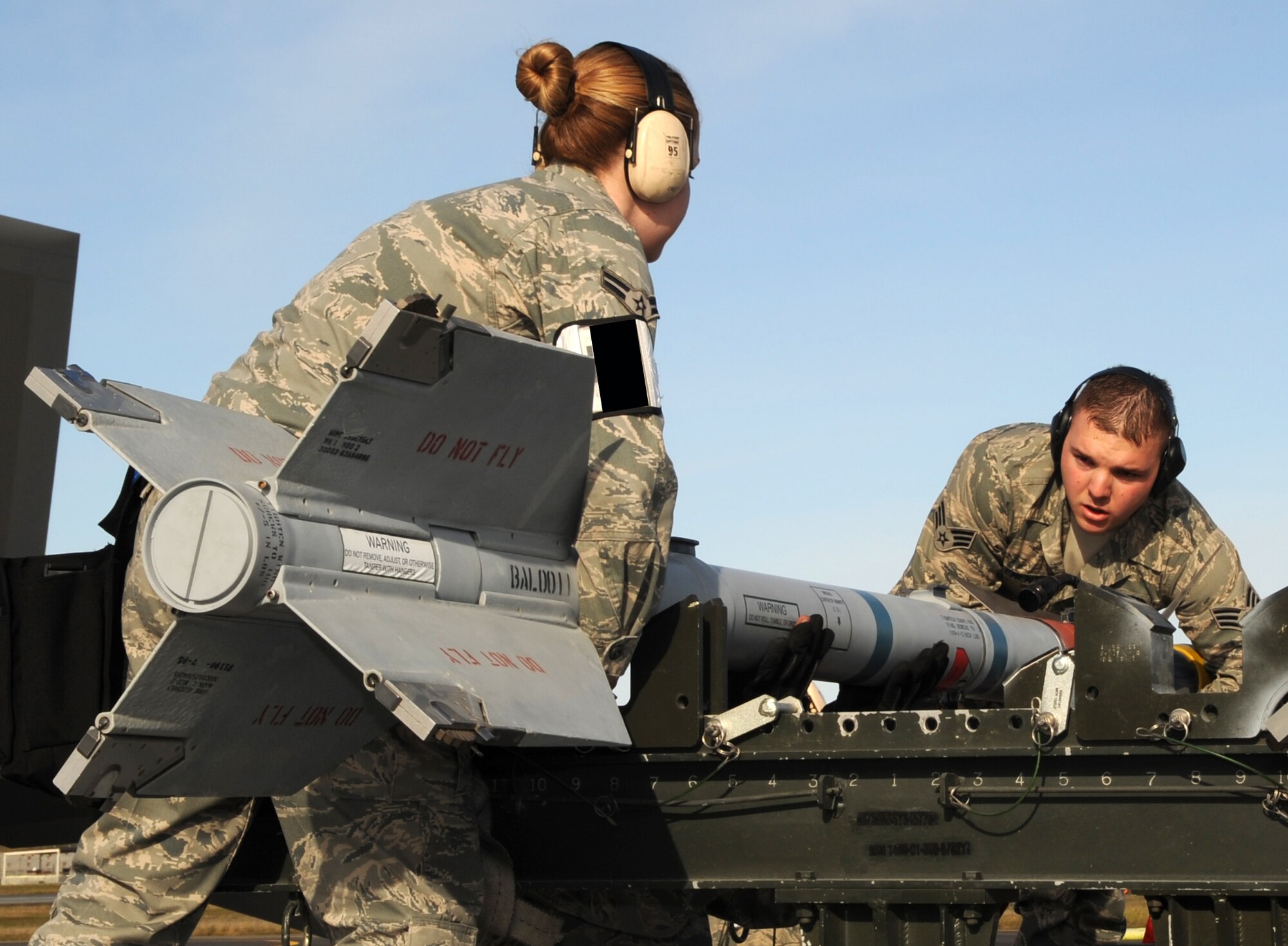 ELMENDORF AIR FORCE BASE, Alaska -- Senior Airman Daniel Clements and Airman 1st Class Shelley Schofield reposition an air intercept missile on a munitions trailor prior to loading on an F-15 Oct 2. Three load teams from the 3rd Wing's Aircraft Maintenance Units participated in a load crew competition on the flight line Oct. 2. Clements and Schofield are Aircraft Armament specialist with the 19th Aircraft Maintenance Unit.   (U.S. Air Force Photo/ Senior Airman Cynthia Spalding) 