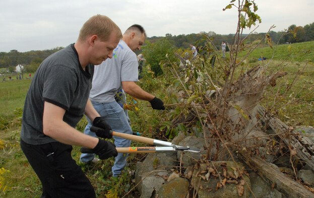 (Left to right) Staff Sgt. Jessie Ogden, 436th Aircraft Maintenance Squadron, and Tech. Sgt. Joe Allen, 736th Aircraft Maintenance Squadron, clip tree branches from the fence lines and stone walls during the annual Gettysburg Cleanup Oct. 2. More than 50 Team Dover volunteers cleared away debris at the Gettysburg National Military Park in Pennsylvania. (U.S. Air Force photo/ Airman 1st Class Shen-Chia Chu)