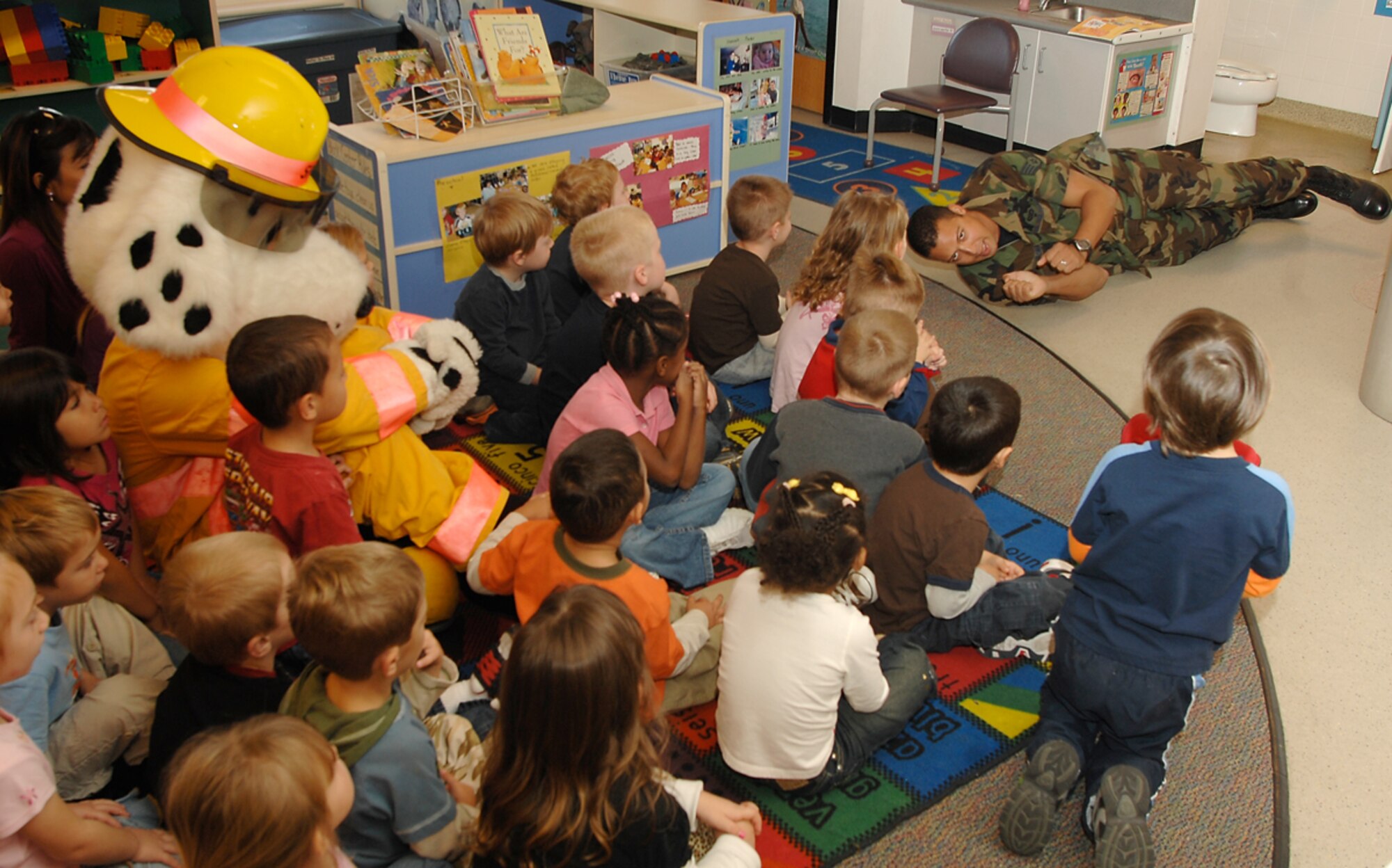 Children and Sparky the Fire Dog watch Staff Sgt. Angel Roman, a 22nd Civil Engineer Squadron firefighter, demonstrate a stop, drop and roll fire safety technique, Oct. 8, 2009, at the child development center at McConnell Air Force Base, Kan. During the demonstration, base firefighters also read books about fire safety and taught children about responding to and surviving a fire situation. (U.S. Air Force photo/Senior Airman Jessica Lockoski)