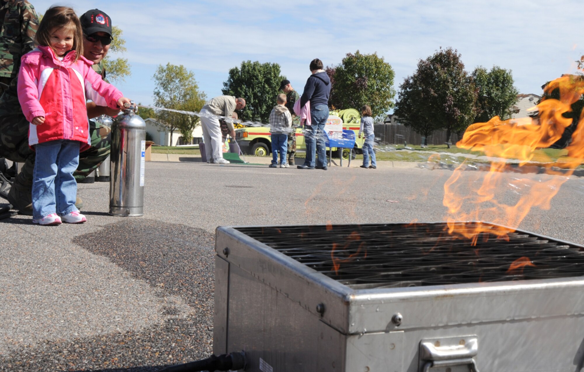 Team McConnell family member, Gabrielle Meier, 3, and Senior Airman Juan Ramirez, a 22nd Civil Engineer Squadron firefighter, put out flames with a fire extinguisher, Oct. 3, 2009, during Fire Prevention Extravaganza at McConnell Air Force Base, Kan. The event introduced McConnell residents to the base fire department and educated youth about fire safety and prevention.  (U.S. Air Force photo/Tech. Sgt. Chyrece Campbell)