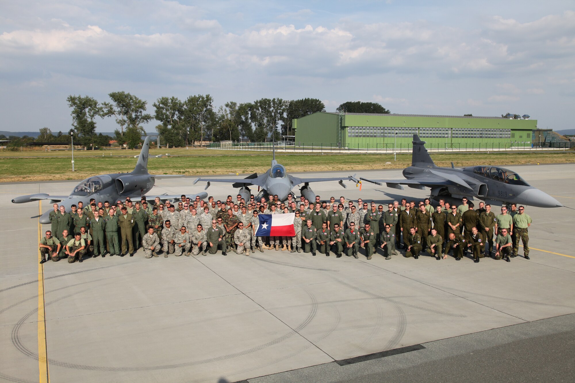Czech and American forces pose together for a photo in front of an F-16 and Czech Grippen and Alca. Members of the Texas Air National Guard’s 149th Fighter Wing were in the Czech Republic conducting mutual training as part of the National Guard’s state partnership program.  (U.S. Air Force photo by Senior Master Sgt Miguel Arellano)
