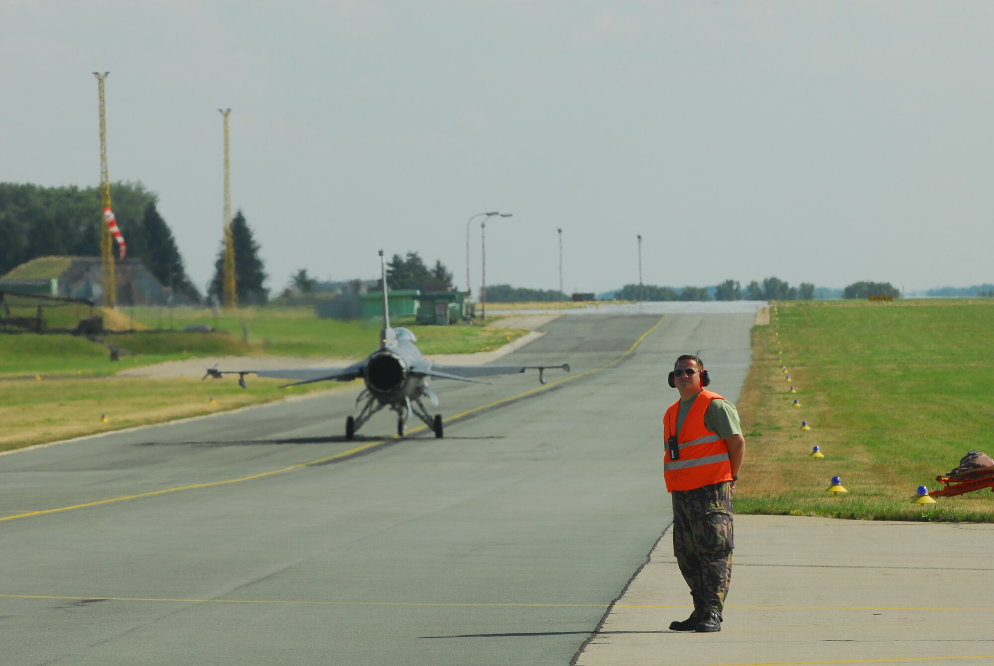 A Czech ground controller stands by as an F-16 taxis past at Caslav Air Base.  Members of the Texas Air National Guard’s 149th Fighter Wing were in the Czech Republic conducting mutual training as part of the National Guard’s state partnership program.  (U.S. Air Force photo by Capt Randy Saldivar)