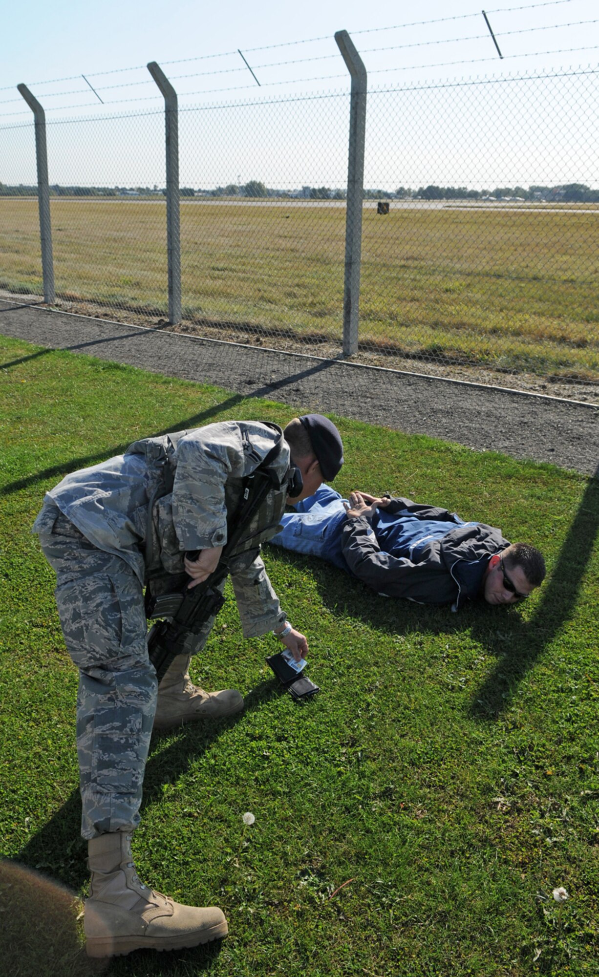 RAF MILDENHALL, England -- Airman 1st Class Garrett Walker, 100th Security Forces Squadron, checks the identification card of Staff Sgt. Nicholas Hoppough, who played the role of a suspect individual in an exercise Oct. 6.  The scenario was part of a two-week Operational Readiness Inspection here. (U.S. Air Force photo/Staff Sgt. Austin M. May)