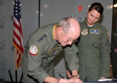 Gen. Duncan McNabb, U.S. Transportation Command commander, signs Master Sgt. Lisa Peele's re-enlistment papers after officiating her re-enlistment on Sgt. Peele's first-ever C-17 flight. Sergeant Peele will attend the First Sergeant Academy beginning Oct. 25 and is designated to become the first sergeant for the 14th Airlift Squadron after graduation. Sergeant Peele's new assignment comes a little more than two years after an accident claimed her husband's life and severely injured her. Her husband had recently attended first sergeant training, as she was preparing to submit her formal application for the First Sergeant Academy when the accident occurred. 
