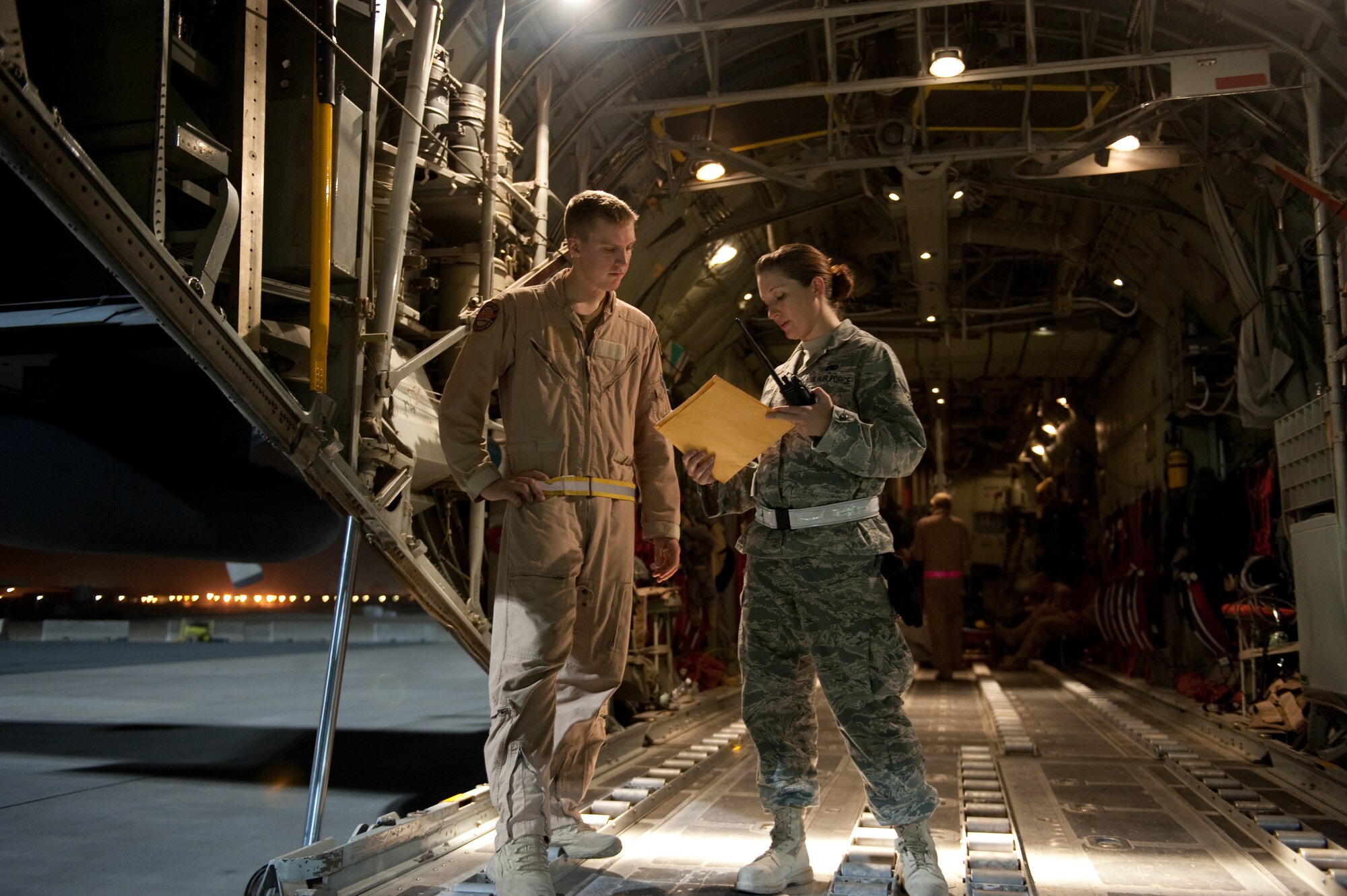 SOUTHWEST ASIA - Right, U.S. Air Force Senior Airman Lacy Champion, 8th Expeditionary Air Mobility Squadron air terminal operations center controller, checks the cargo and passenger manifest with Staff Sgt. Robert Farland, 30th Airlift Squadron loadmaster, Oct. 6, 2009, in Southwest Asia. Airman Champion helps ensure all local cargo aircraft have their cargo and passenger unloaded and loaded correctly, timely and safely. Airman Champion is deployed from Dover Air Force Base, Del., and Sergeant Farland is deployed from Cheyenne, Wyo., both are in support of operations Iraqi Freedom and Enduring Freedom. (U.S. Air Force photo/Staff Sgt. Robert Barney/RELEASED) 