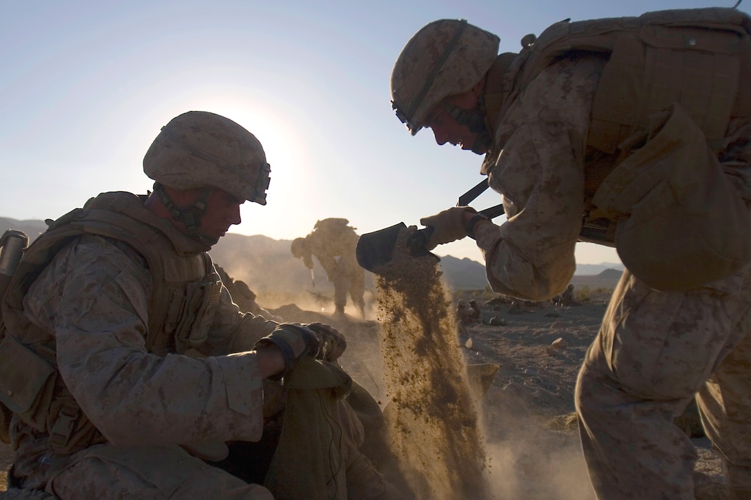 U.S. Marine Corps Lance Cpl. Michael A. Kelley, left, dumps a shovel of sand into a sandbag held by Lance Cpl. William I. Holdsworth while preparing their fighting position for the “hold” portion during Enhanced Mojave Viper, an exercise on Marine Corps Air Ground Combat Center, Twentynine Palms, Calf., Sept. 27, 2009. Both are assigned to Bravo Company, 1st Battalion, 3rd Marine Regiment.