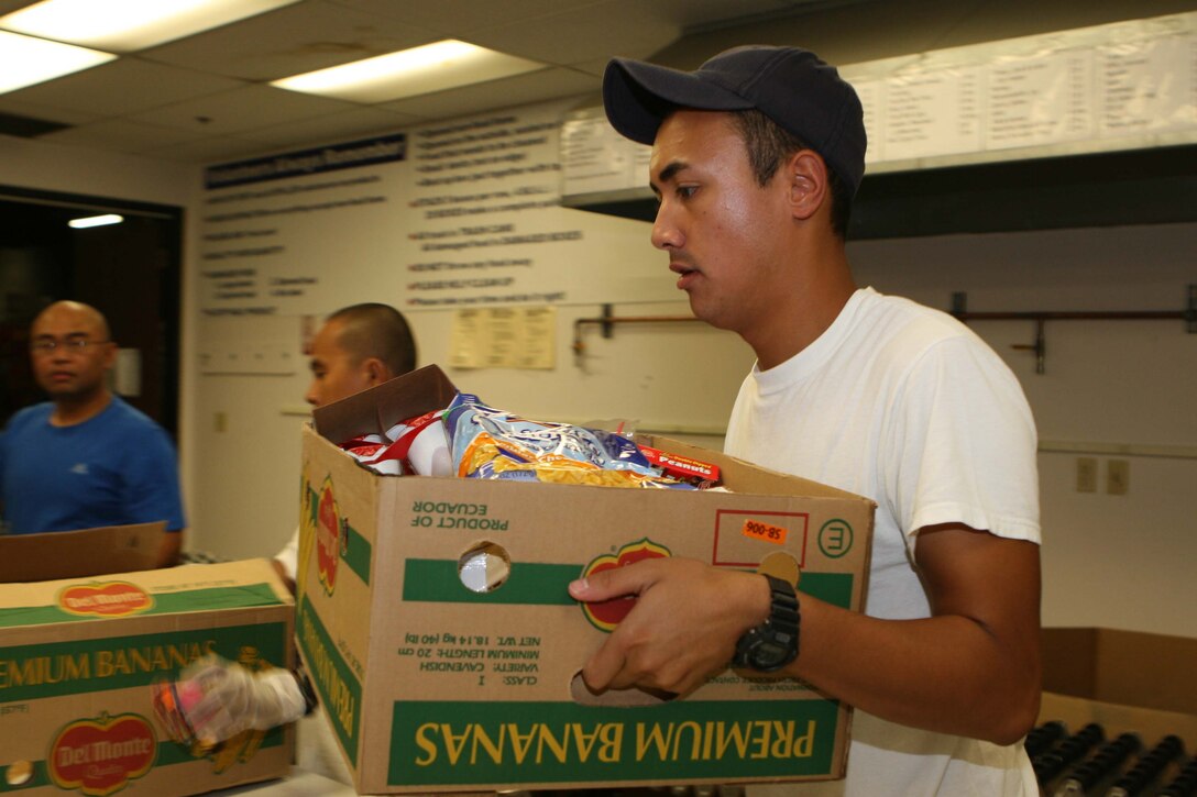 CECN Michael Testa, from Naval Air Base Coronado, carries a box of inspected food items from the quality control room at Feeding America San Diego. The armed services YMCA gathered active duty volunteers from five San Diego military installations to help gather, sort and box food items for the needy Oct. 8.