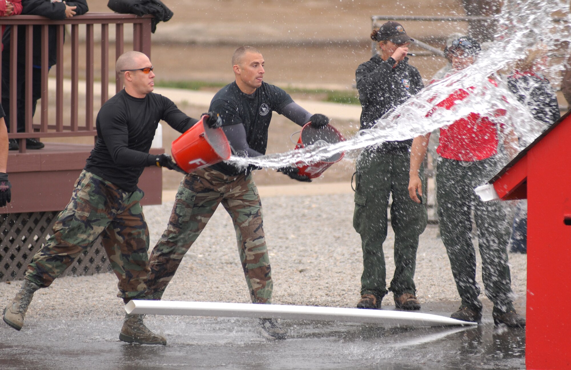 VANDENBERG AIR FORCE BASE, Calif. -- Members of Team V toss buckets full of water onto a simulated burning building here Oct. 9 for the 3rd Annual Fire Muster competition. The competition is held every year to demonstrate the physical demands of firefighters.(U.S. Air Force photo/Airman 1st Class Kerelin Molina)


