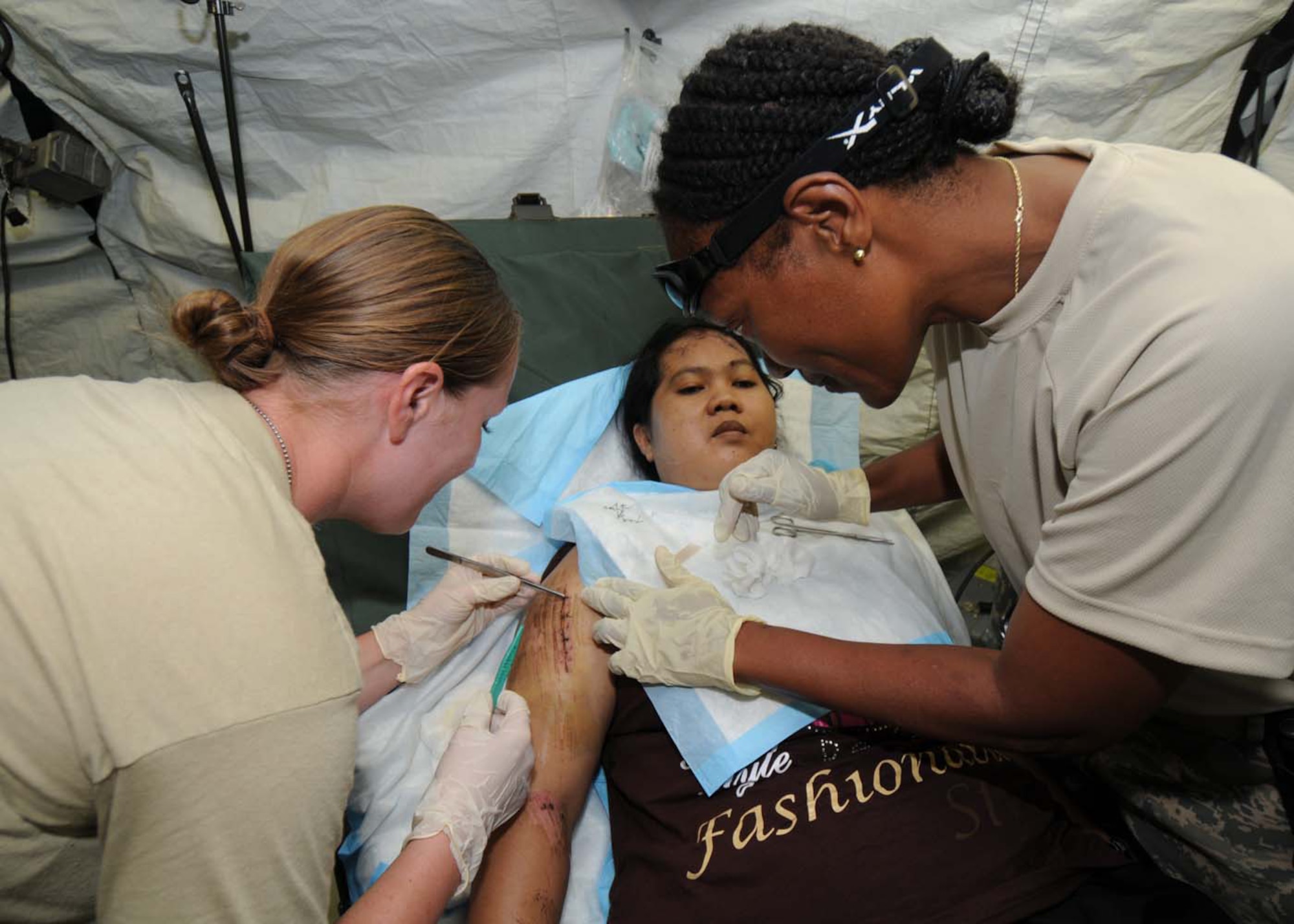 Staff Sgt. Beth Sherman (left) and Maj. Brenda Parker remove sutures in a mobile field hospital in Padang, Indonesia, Oct. 8. Sergeant Sherman, an individual duty medical technician, and Major Parker, a nurse, are deployed from the 36th Medical Group at Andersen Air Force Base, Guam, as part of an Air Force humanitarian assistance rapid response team. (U.S. Air Force photo/Staff Sgt. Veronica Pierce)