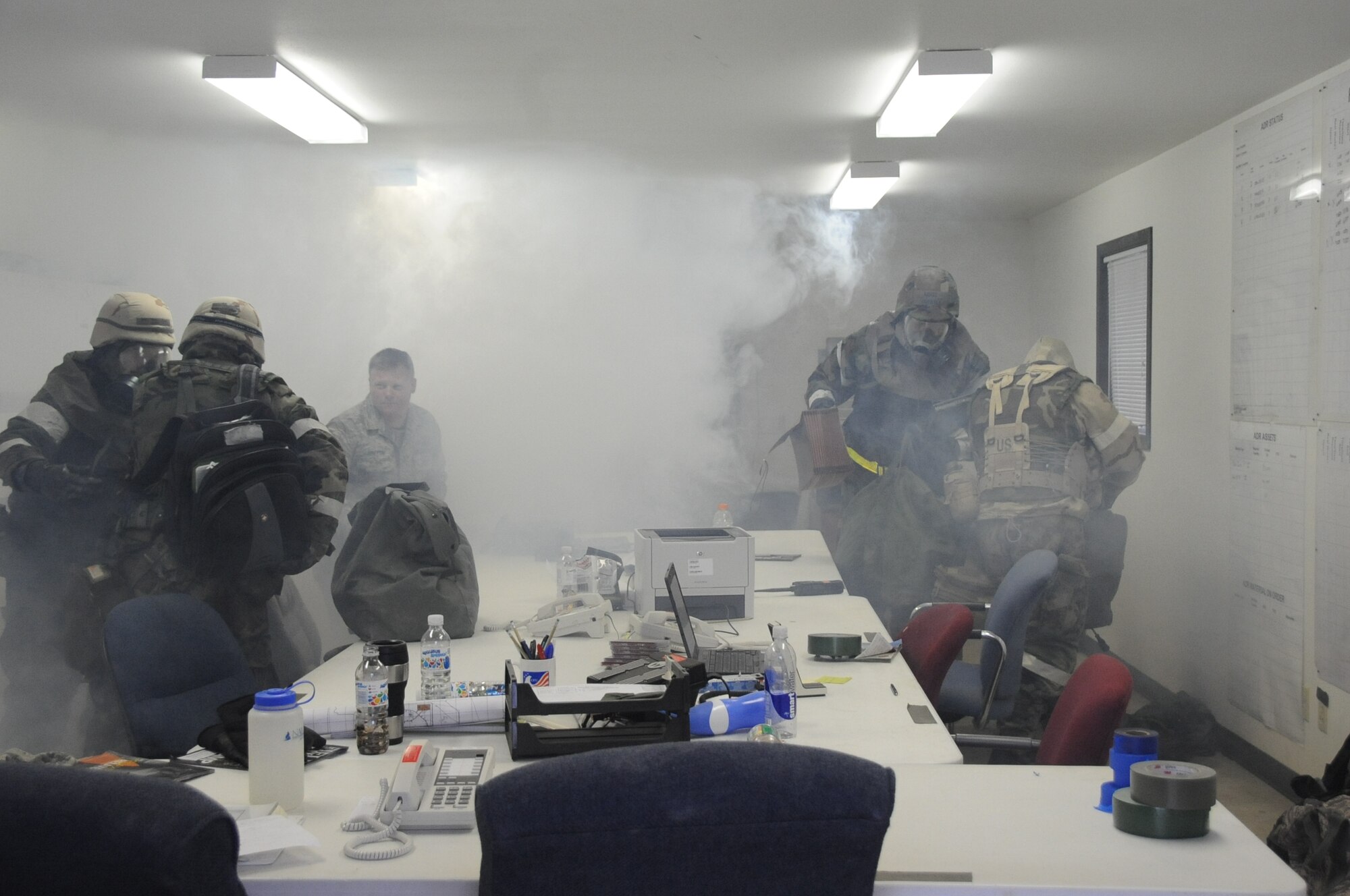 Airmen from the 28th Civil Engineer Squadron quickly grab their equipment as smoke fills the building in a simulated fire during a Phase II Operational Readiness Exercise here, October 7.  The building fills with a non-toxic smoke to not only train Airmen on escaping, but to train firefighters on search and rescue as well. (U.S. Air Force photo/Airman 1st Class Anthony Sanchelli)