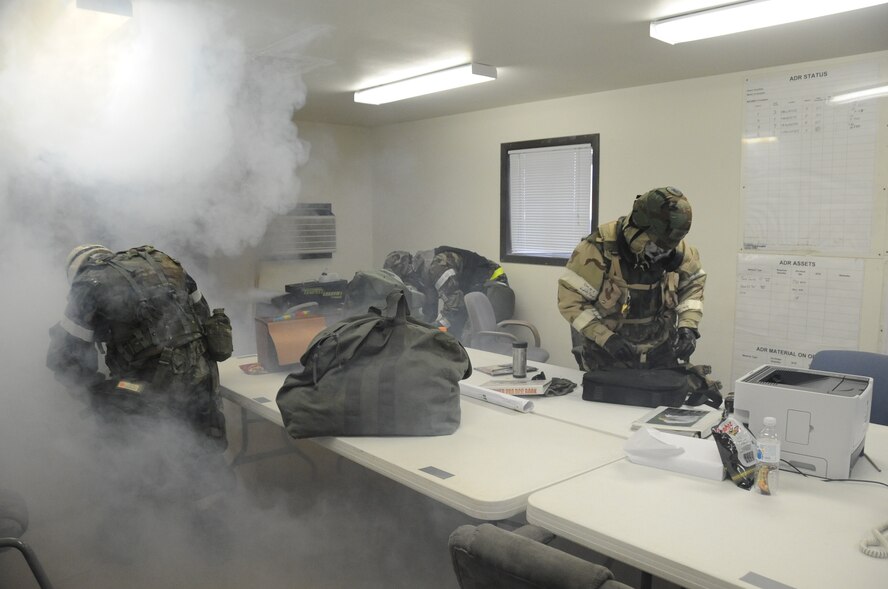 Airmen from the 28th Civil Engineer Squadron quickly grab their equipment as smoke fills the building in a simulated fire during a Phase II Operational Readiness Exercise here, October 7.  The building fills with a non-toxic smoke to not only train Airmen on escaping, but to train firefighters on search and rescue as well. (U.S. Air Force photo/Airman 1st Class Anthony Sanchelli)