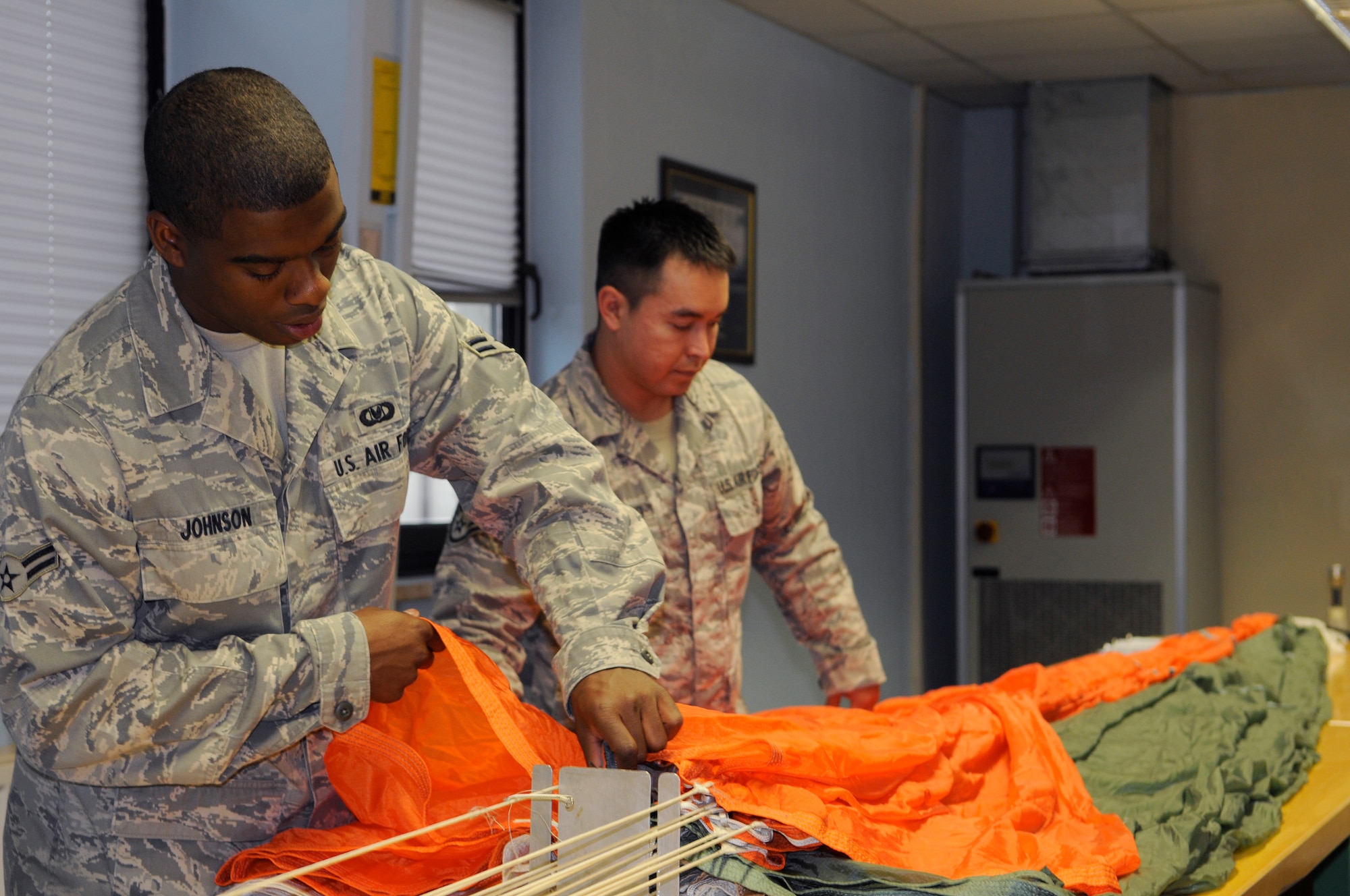 SPANGDAHLEM AIR BASE, Germany – Airman 1st Class Alexander Johnson and Staff Sgt. Ronald Armstrong, both 52nd Operations Support Squadron aircrew flight equipment technicians, air out the canopy of a parachute before folding and packing it Oct. 6. During this portion of the packing process the technicians perform a quality check and look for tears or damage to the canopy. (U.S. Air Force photo/Senior Airman Benjamin Wilson)