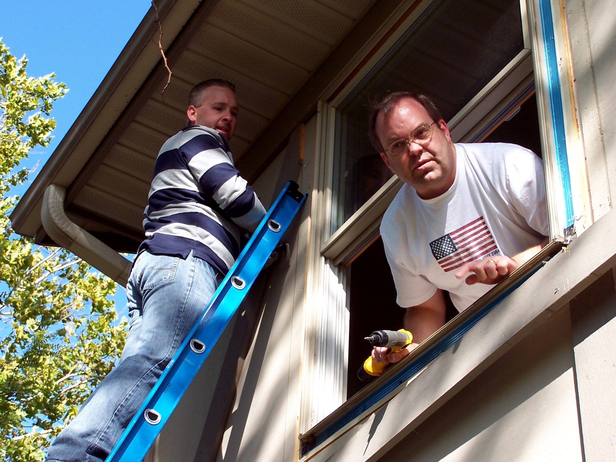 Jason McIntosh (left) and Brian Barrett (right) both from Air Force Research Laboratory Enterprise Business Systems work on removing a second story window for the ReSale store for the Habitat for Humanity.  The window would be resold at the Habitiat for Humanity ReSale store which proceeds go to build a Habitat house. (Air Force Photo\Ted Theopolos)