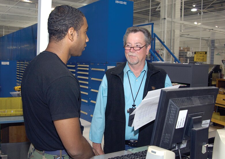 Rick Tripp talks tools with co-worker Senior Airman Christopher Edwards in the Bldg. 3001 main tool crib recently. Mr. Tripp can’t walk down the aisle from his new job with 76th Maintenance Support Group without people doing a double take or stopping to greet him. (Air Force photo by Margo Wright) 