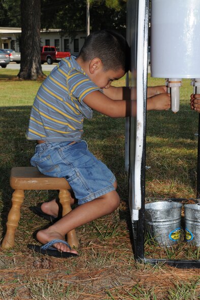 A family member of the 916th Air Refueling Wing 'milks a cow', one of many games offered during the Family Day Picnic Oct. 3.  (U.S. Air Force photo by Gillian M. Albro, 916th ARW/PA)