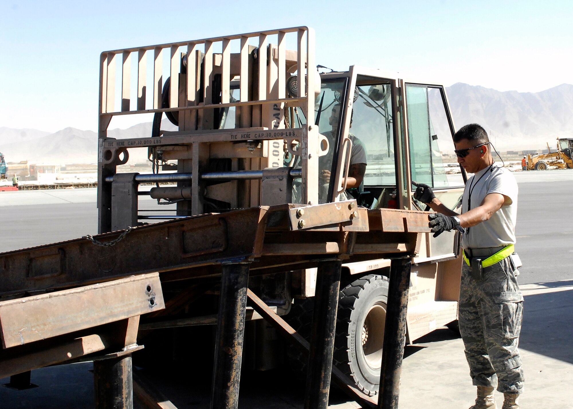 BAGRAM AIRFIELD, Afghanistan -- Master Sgt. Oscar Iruegas (standing), the Ramp Supervisor form the 455th Expeditionary Aerial Port Squadron, directs Senior Airman Alfred Garcia (driving), a member of the ramp load team from the 455th EAPS, on where he needs to move the ramp here, Oct. 9, 2009.  This mission essential ramp was offloaded and stored on the flightline by the 455th EAPS.  Sergeant Iruegas and Airman Garcia are both deployed from Lackland Air Force Base, Texas and hail from San Antonio, Texas.  (U.S. Air Force photo/Senior Airman Felicia Juenke)