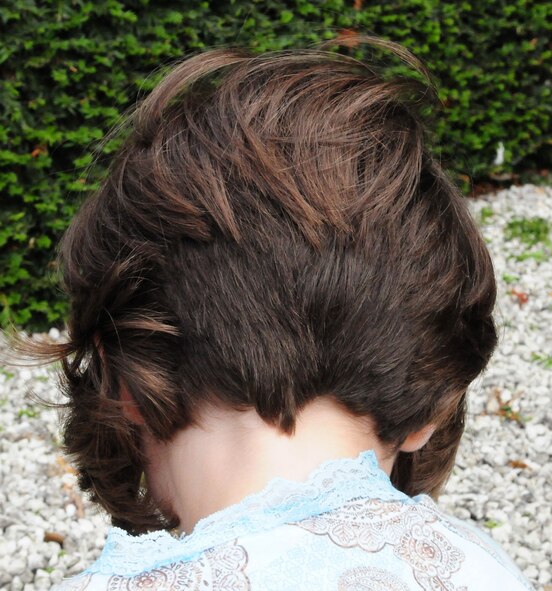 Noel Ingram shows off the finished result of her drastic haircut, which she had done so another little girl in the United States or Canada would also be able to have hair, in the form of a hairpiece (which will be made from Noel's cut hair). (U.S. Air Force photo by Karen Abeyasekere)