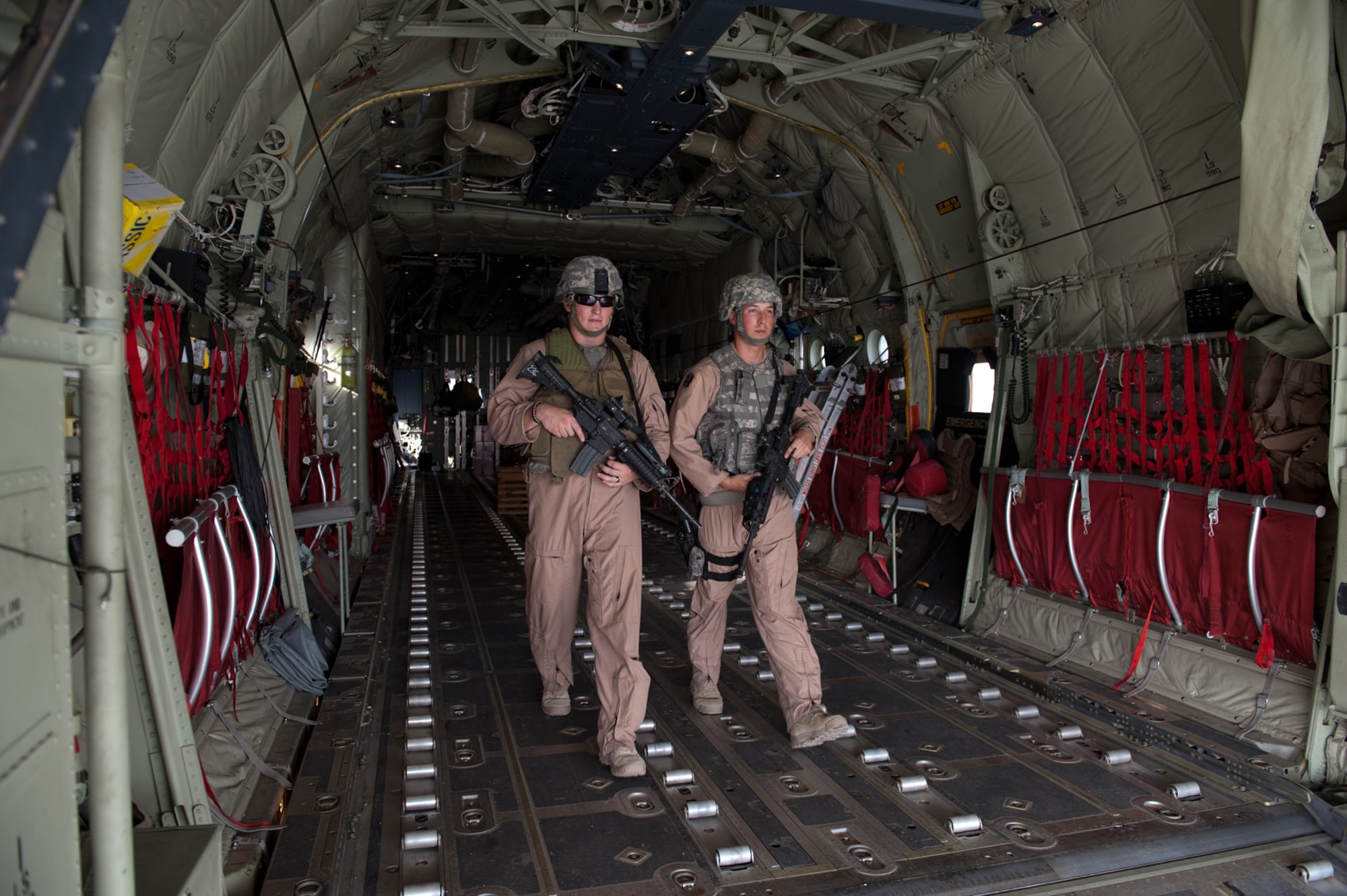 Left, U.S. Air Force Airman 1st Class Dustin Wiley and Senior Airman Brandon Owens, 379th Expeditionary Security Forces Squadron Fly Away Security Team members, exit a C-130 as they secure the area around the aircraft, Oct. 6, in Southwest Asia. Airmen Wiley and Owens ensures U.S. Air Force aircraft are secure when they travel to areas with less established security. Airman Wiley is deployed from RAF Mildenhall, England, and Airmen Owens is from Bolling Air Force Base, Washington D.C. Both are deployed in support of Operations Iraqi and Enduring Freedom. (U.S. Air Force photo/Staff Sgt. Robert Barney/RELEASED)