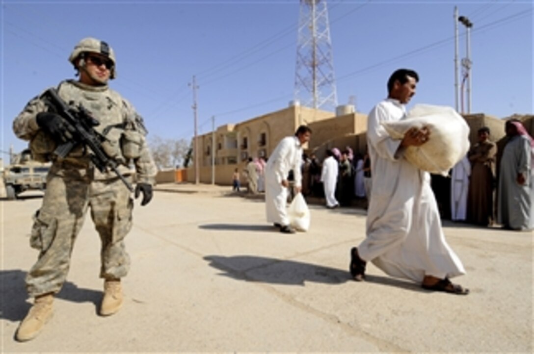 U.S. Army Spc. Nathan Swelfer, assigned to Charlie Troop, 6th Squadron, 9th Cavalry Regiment, 1st Cavalry Division, stands guard as locals walk away with food supplies distributed to them by the soldiers and Iraqi police officers during a humanitarian aid mission at the government headquarters building in the town of Biaj, near Sinjar, Iraq, on Oct. 1, 2009.  